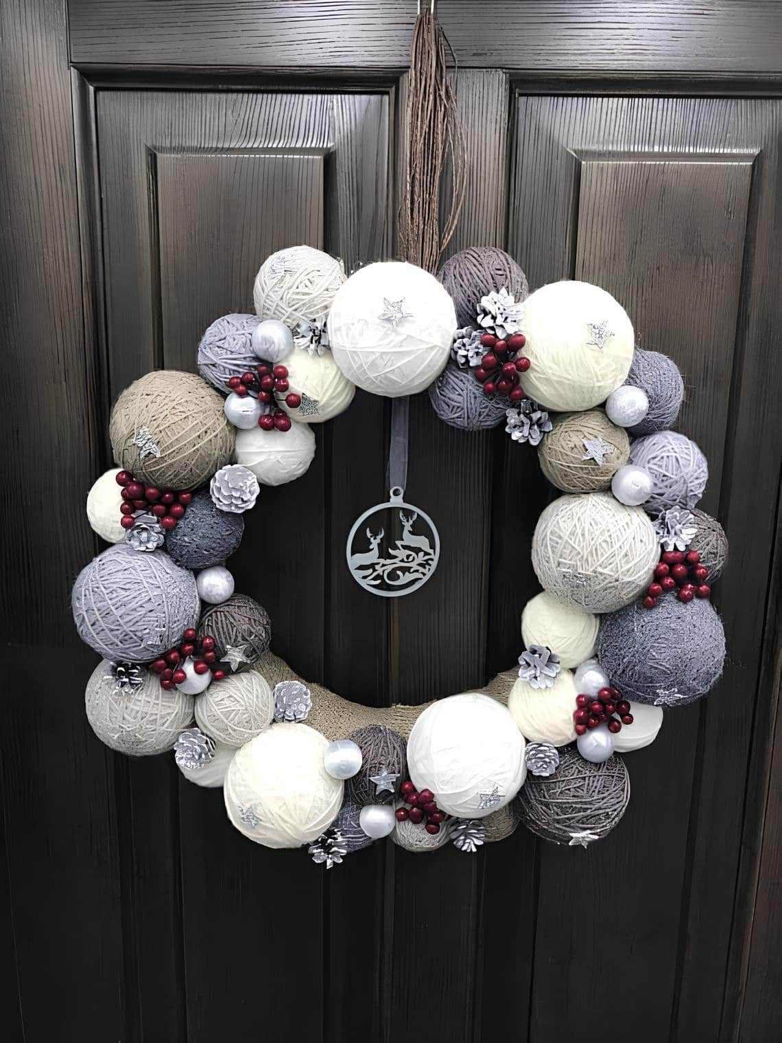 DIY Christmas wreath made from yarn balls in neutral tones with red berries