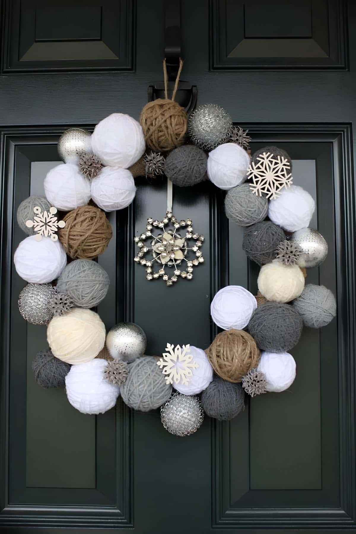 Christmas wreath made of yarn balls in gray, white, and brown with snowflake accents