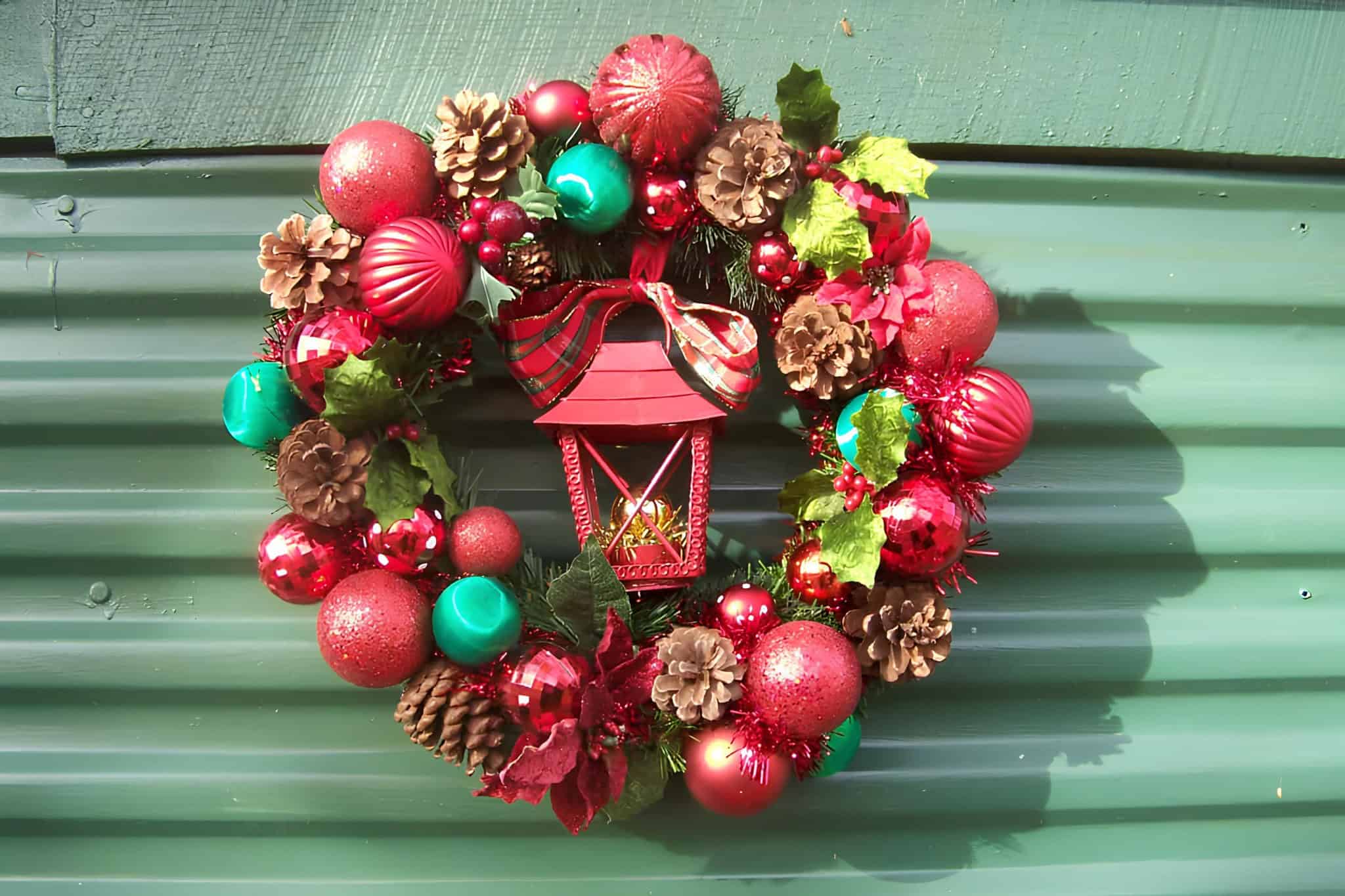 Traditional lantern wreath with red bow, green and gold ornaments, and pinecones