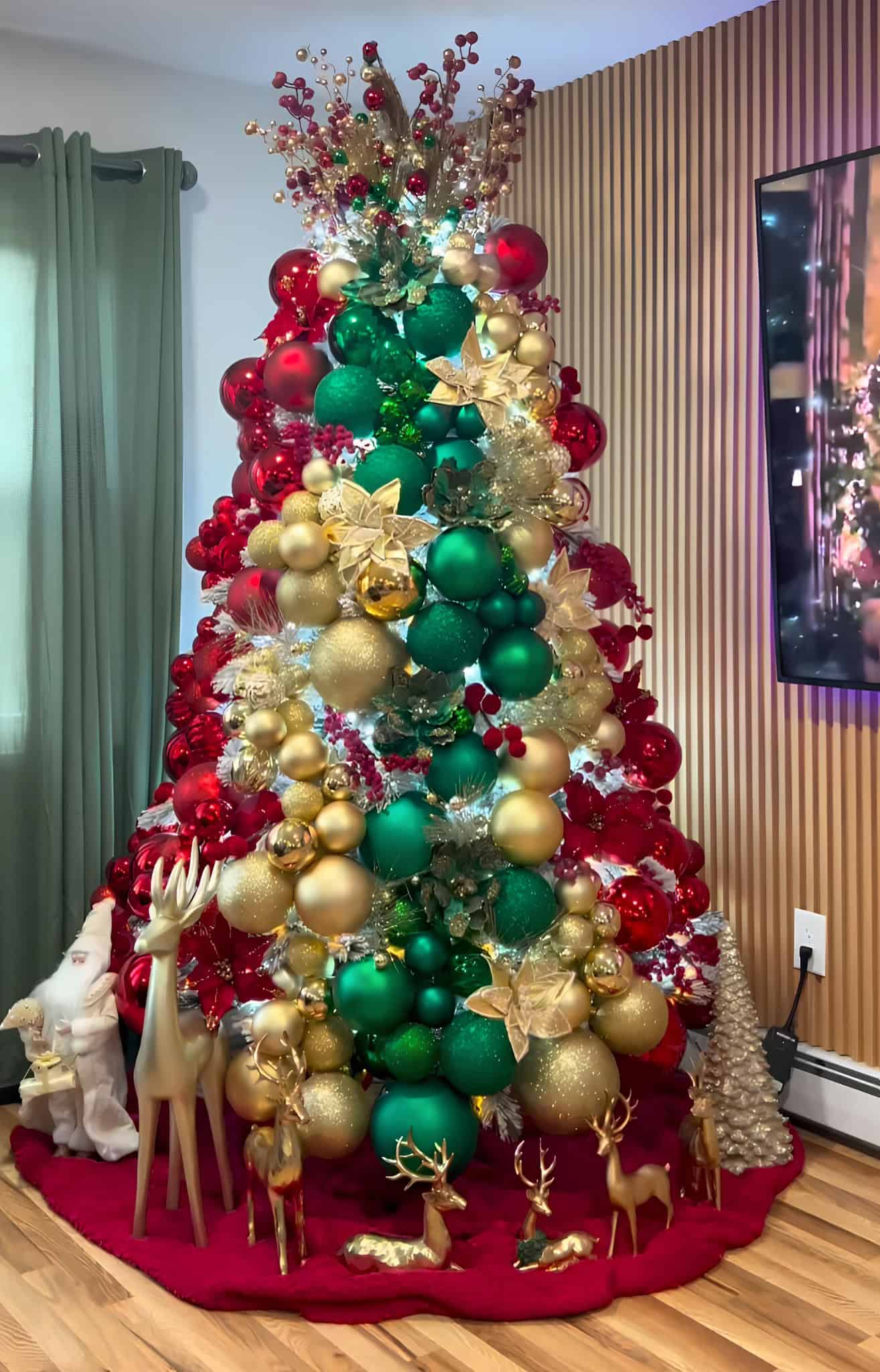 Classic red, green, and gold Christmas tree with reindeer ornaments and traditional design