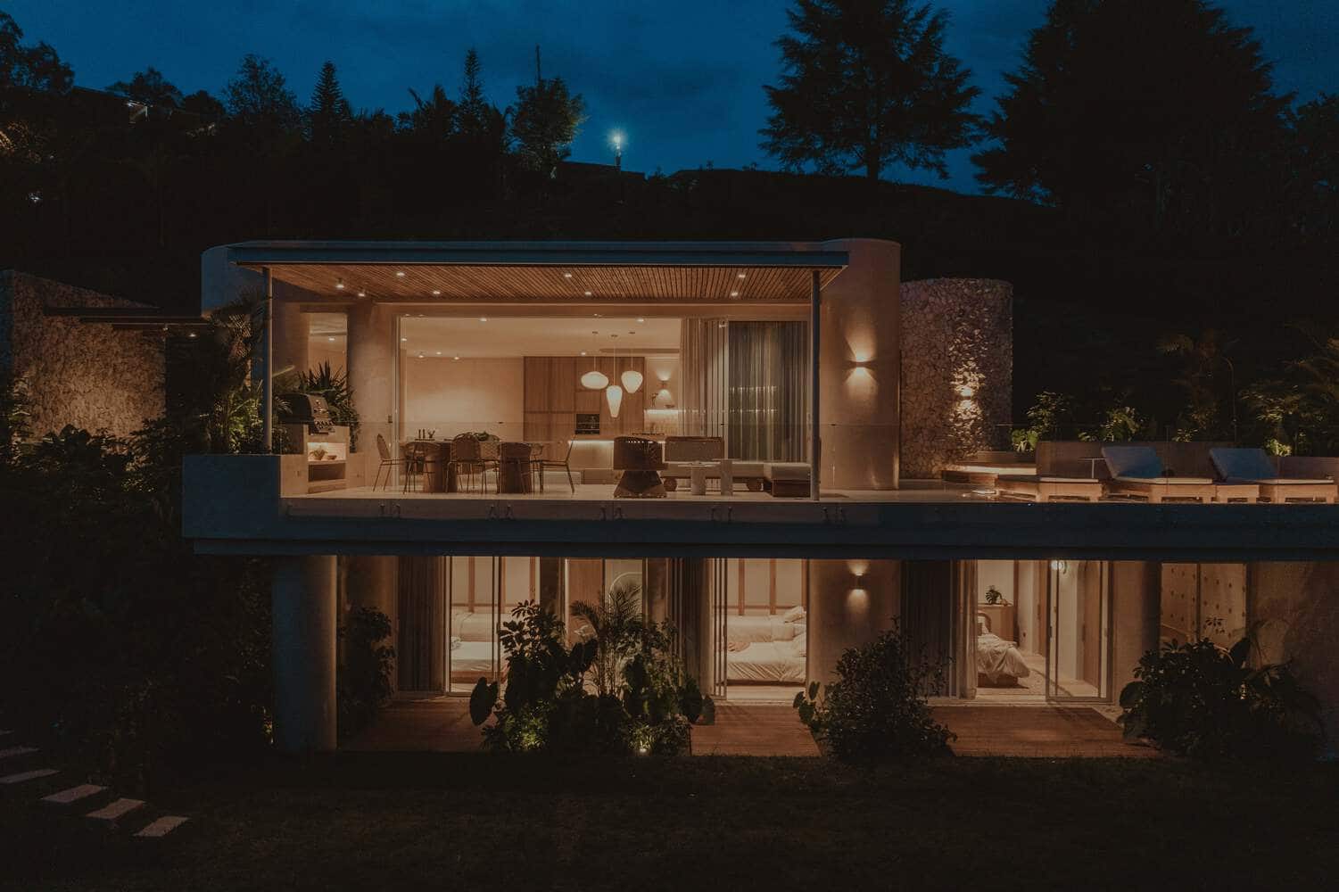 Contemporary modern house with open-plan living space, glass walls, outdoor terrace, and stylish interior design illuminated at night. Perfect example of luxury architecture and modern home architecture.
