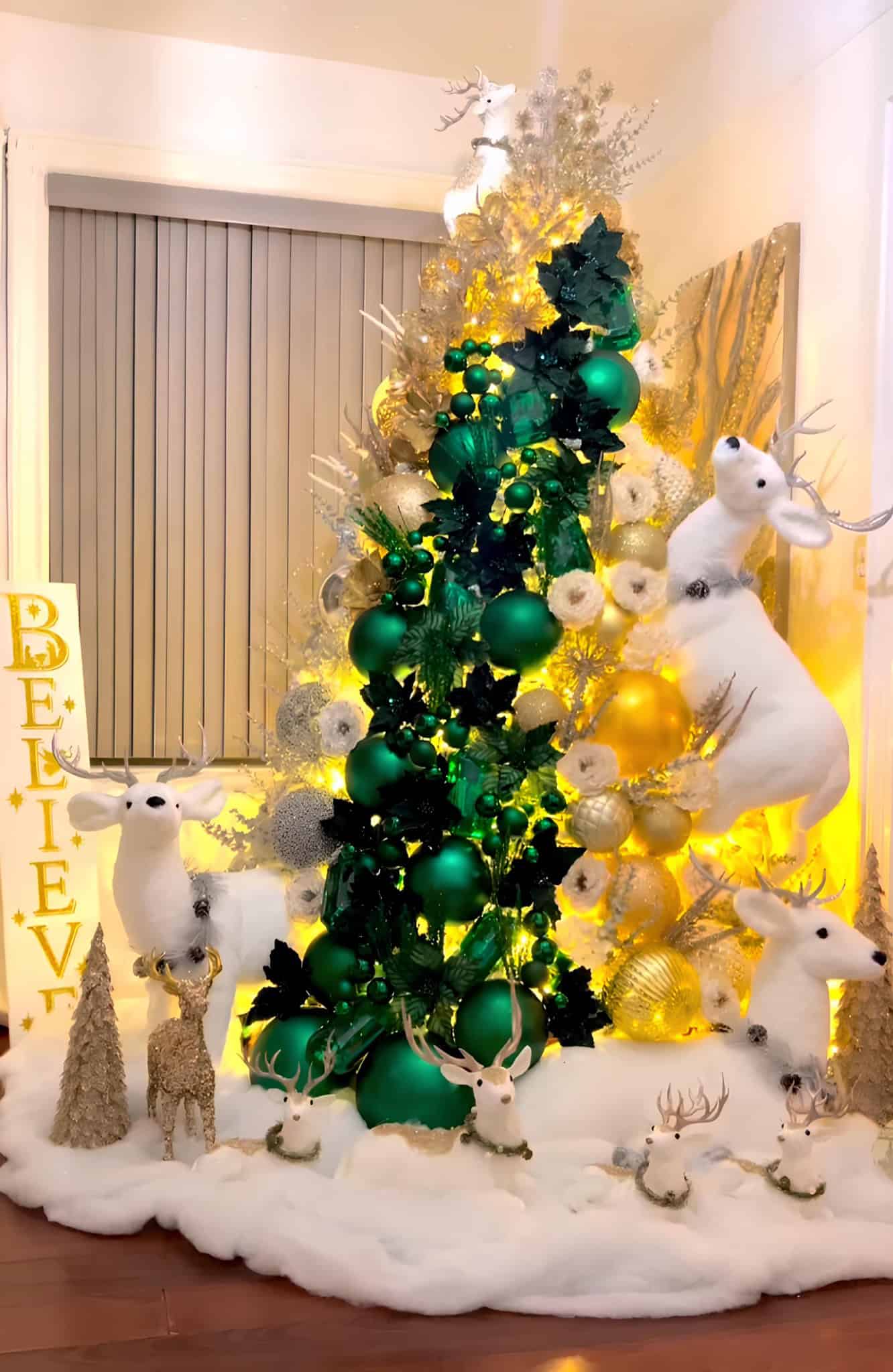 Emerald and gold Christmas tree with reindeer ornaments and snow base