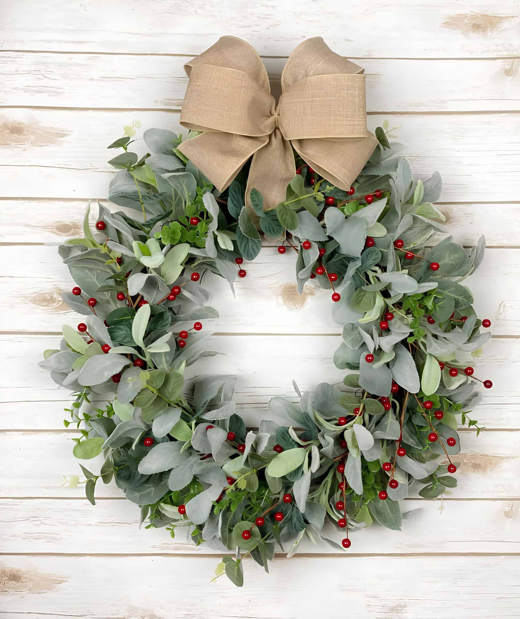 Muted eucalyptus Christmas wreath with red berries and a neutral linen bow