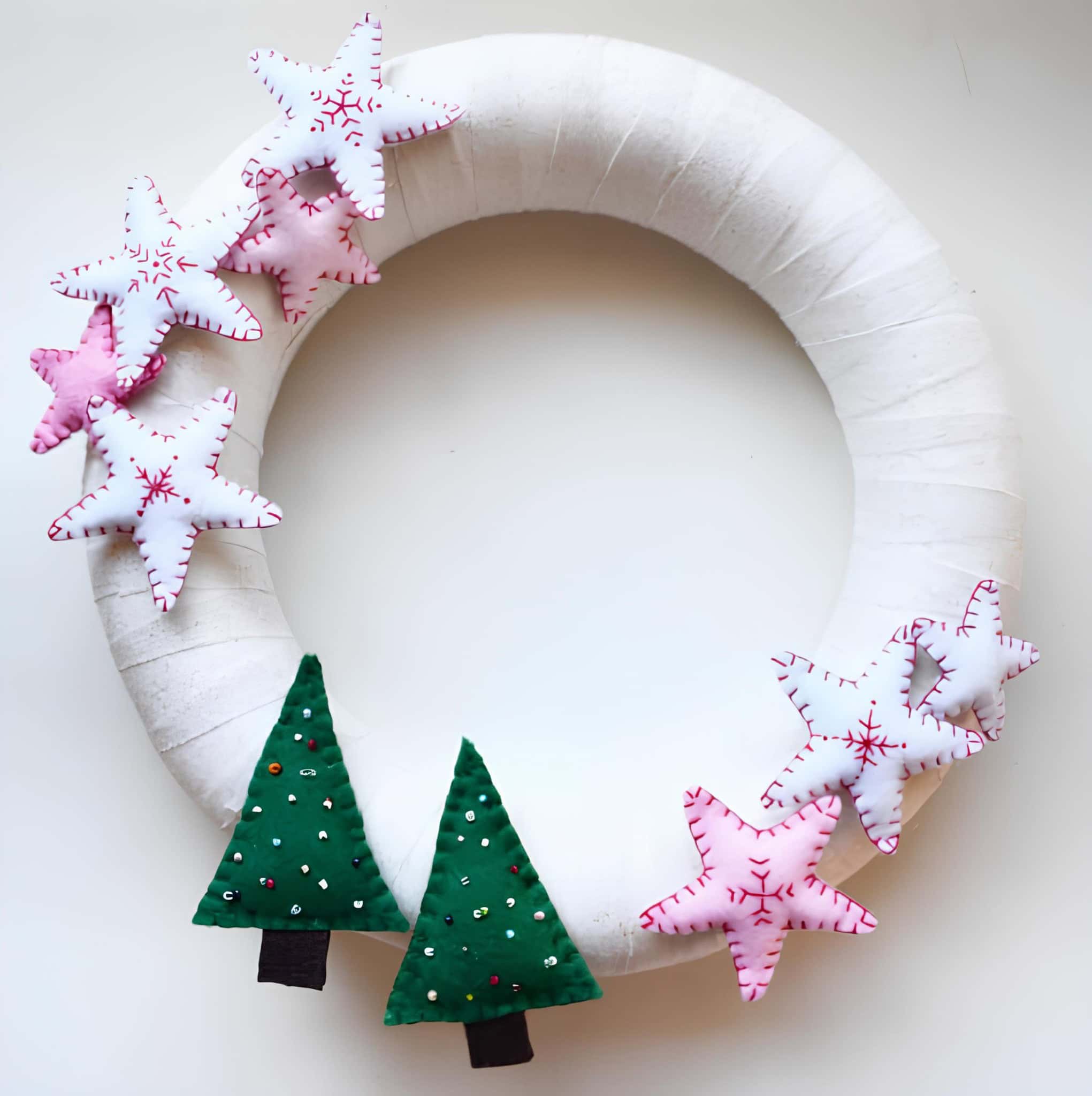 Handmade felt white wreath decorated with pink stars and green Christmas trees