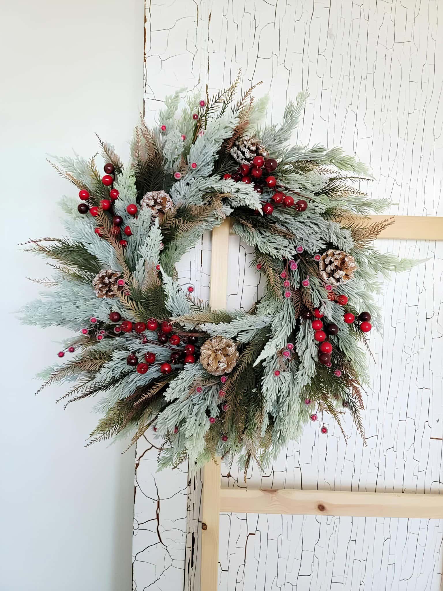 Frosted winter wreath with snowy greenery, pinecones, and red berries