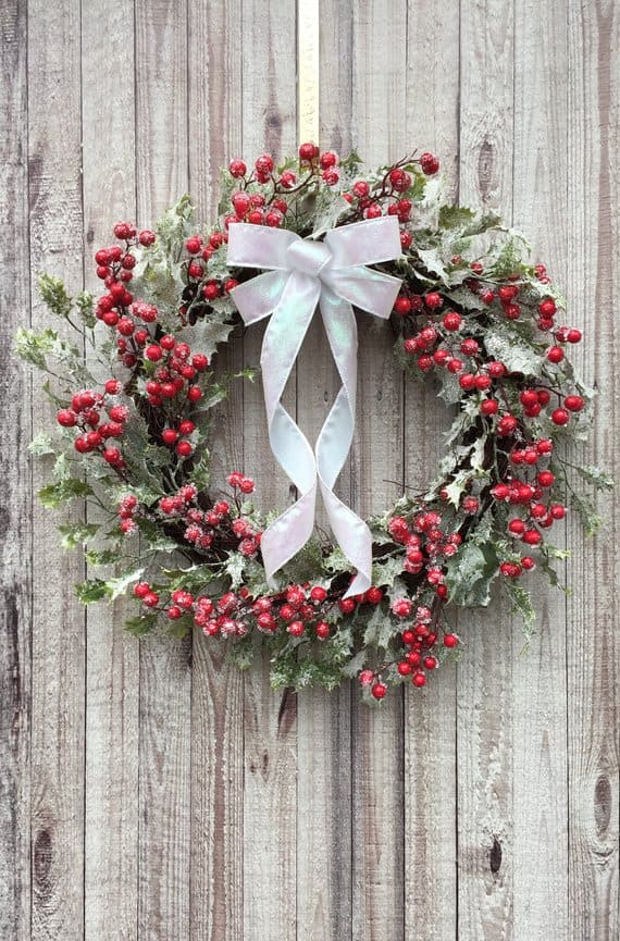 Snow-covered berry Christmas wreath with white satin bow