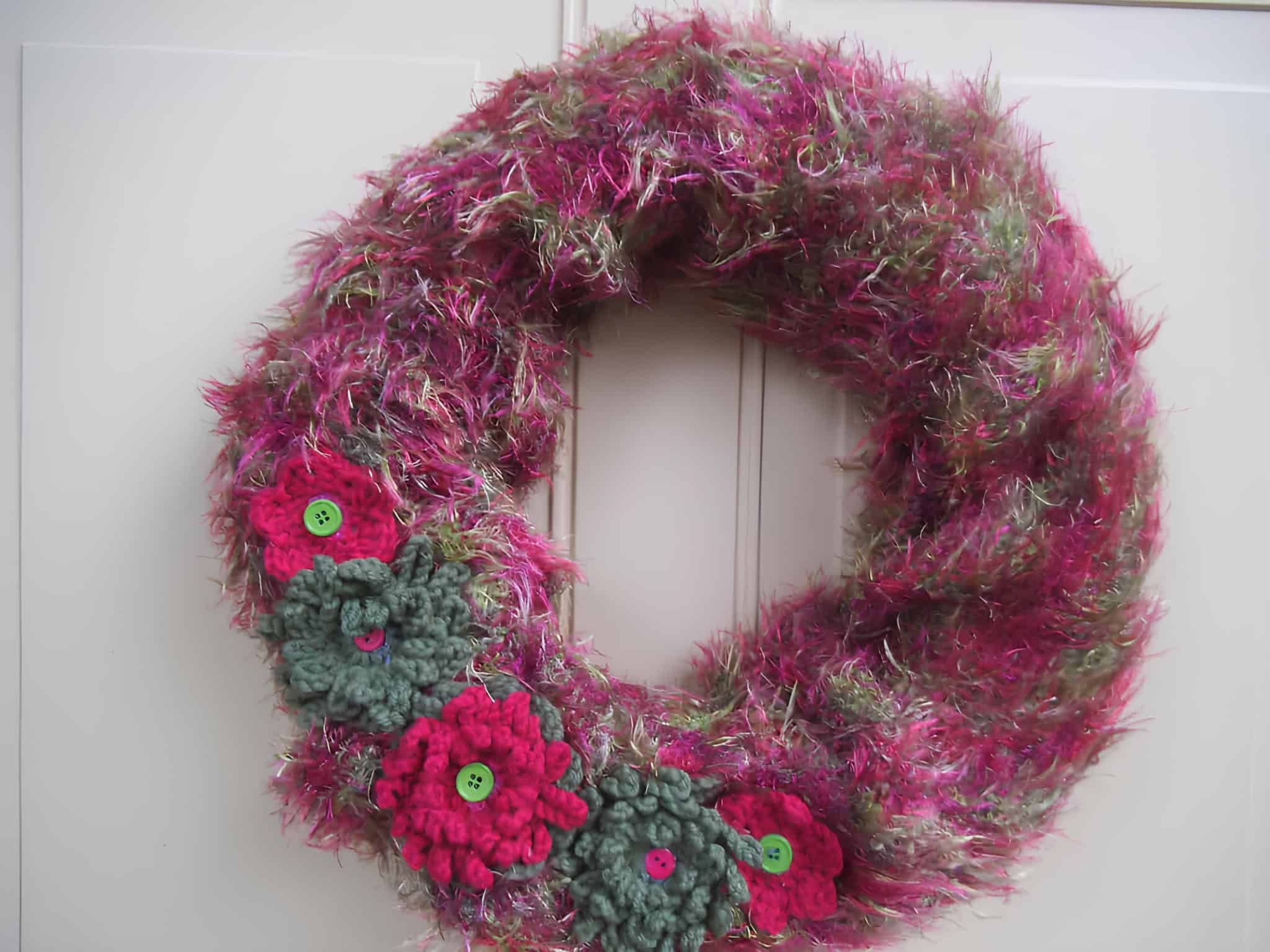 Handmade fuzzy yarn Christmas wreath decorated with crochet flowers and buttons