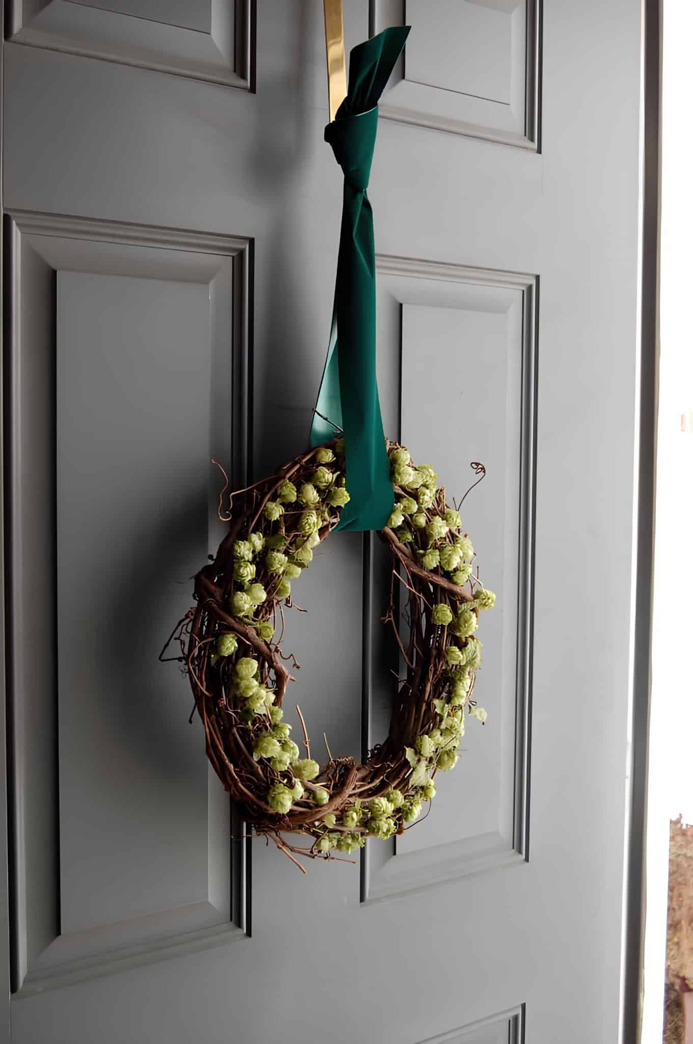 Natural grapevine wreath adorned with green hops cones and a long green hanger