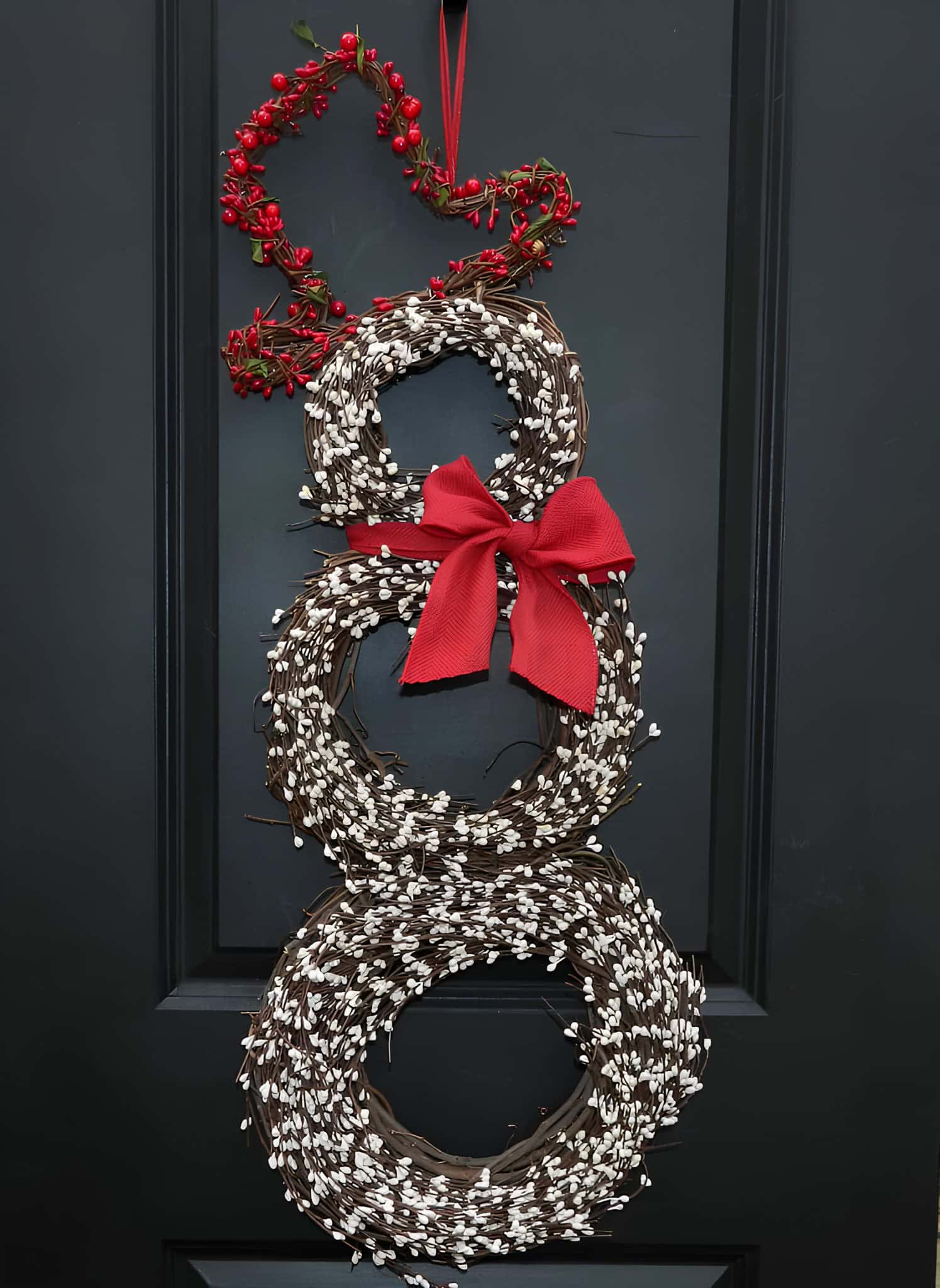 Stacked grapevine snowman wreath accented with white berries, red bow, and berry antlers