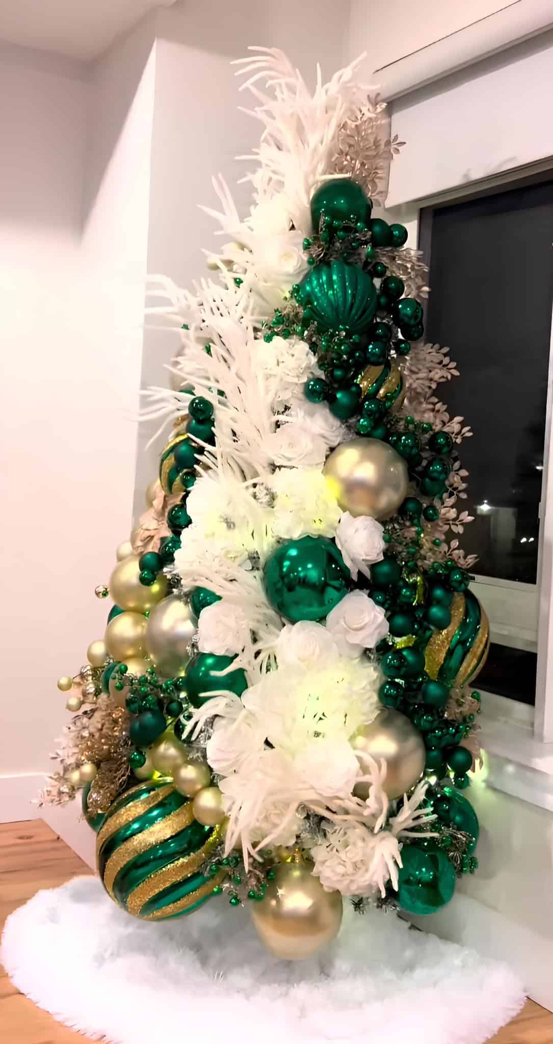 Green and gold luxury Christmas tree with large baubles and white florals