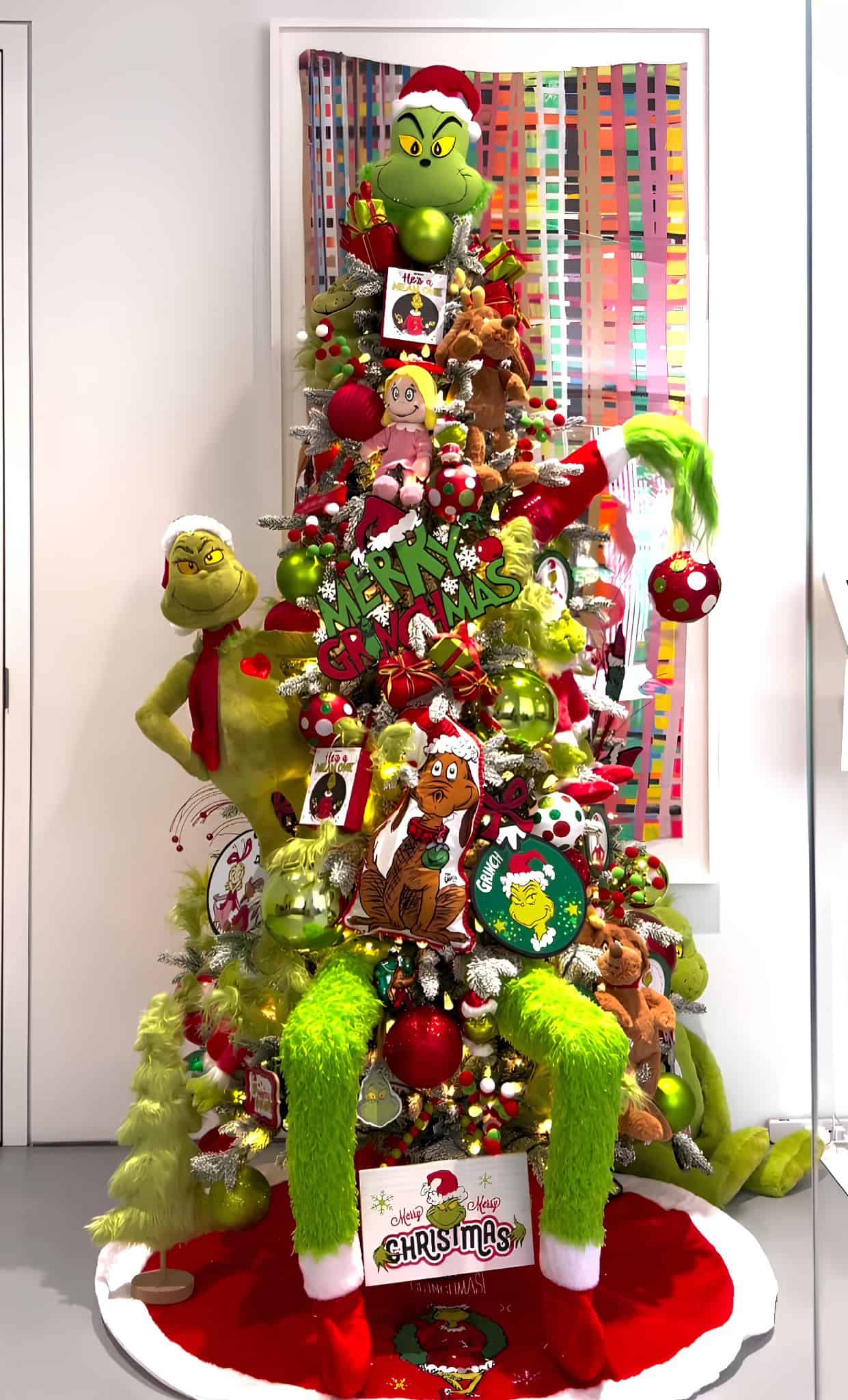 Whimsical Grinch-themed Christmas tree with plush toys, red and green ornaments, and playful accents
