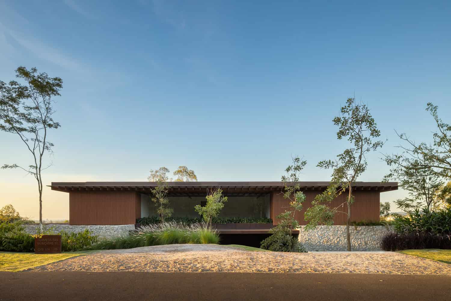 Sleek modern house with flat roof and natural stone accents, surrounded by landscaping, under a clear blue sky, exemplifying contemporary architecture design and eco-friendly building concepts.