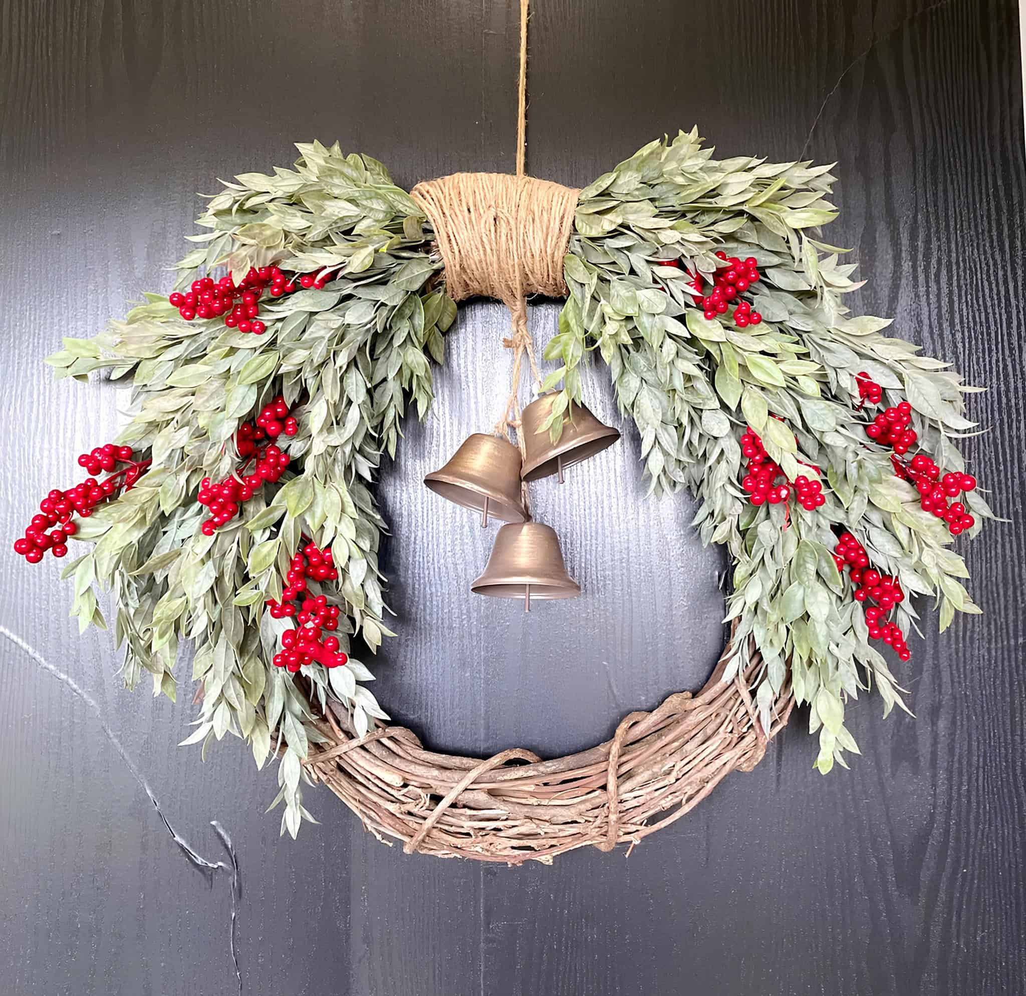Asymmetrical laurel wreath with red berries and hanging bronze bells