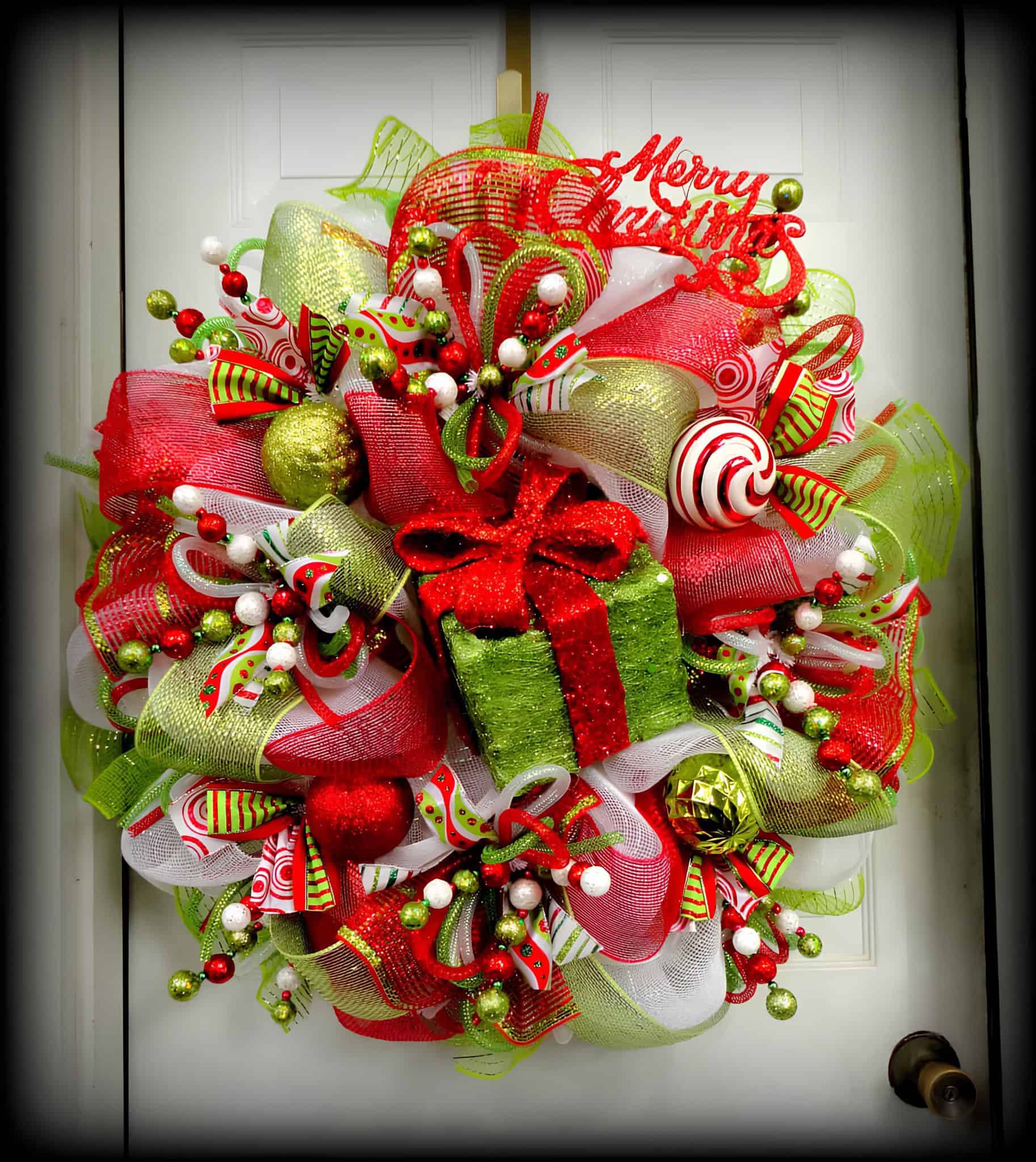 Festive ribbon wreath with glittered lime green present centerpiece and red accents