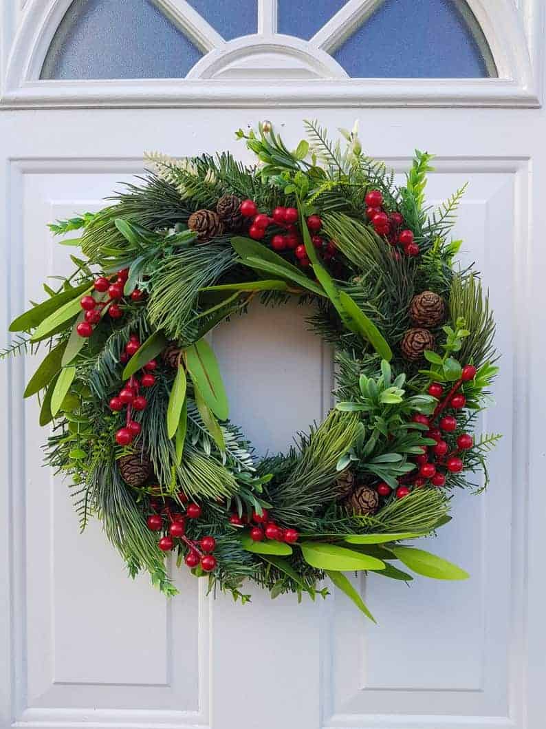 Holiday wreath with mistletoe leaves, pinecones, and red berries
