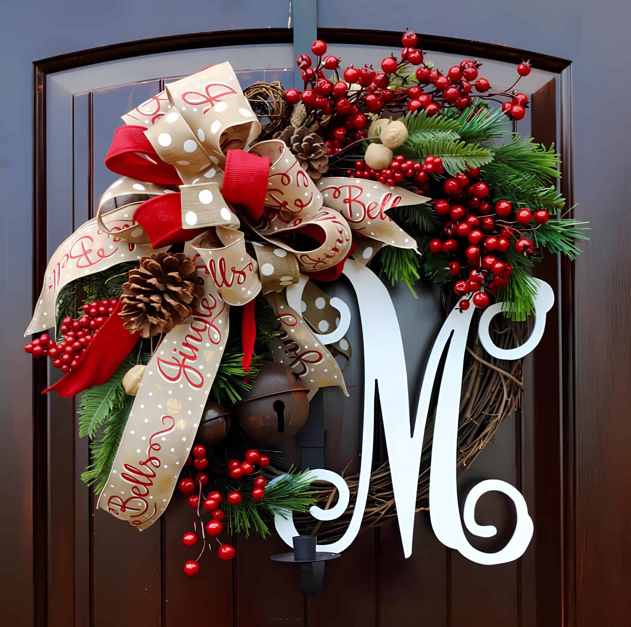 Festive wreath with big polka-dot bow, red berries, pinecones, bells and a white monogram letter