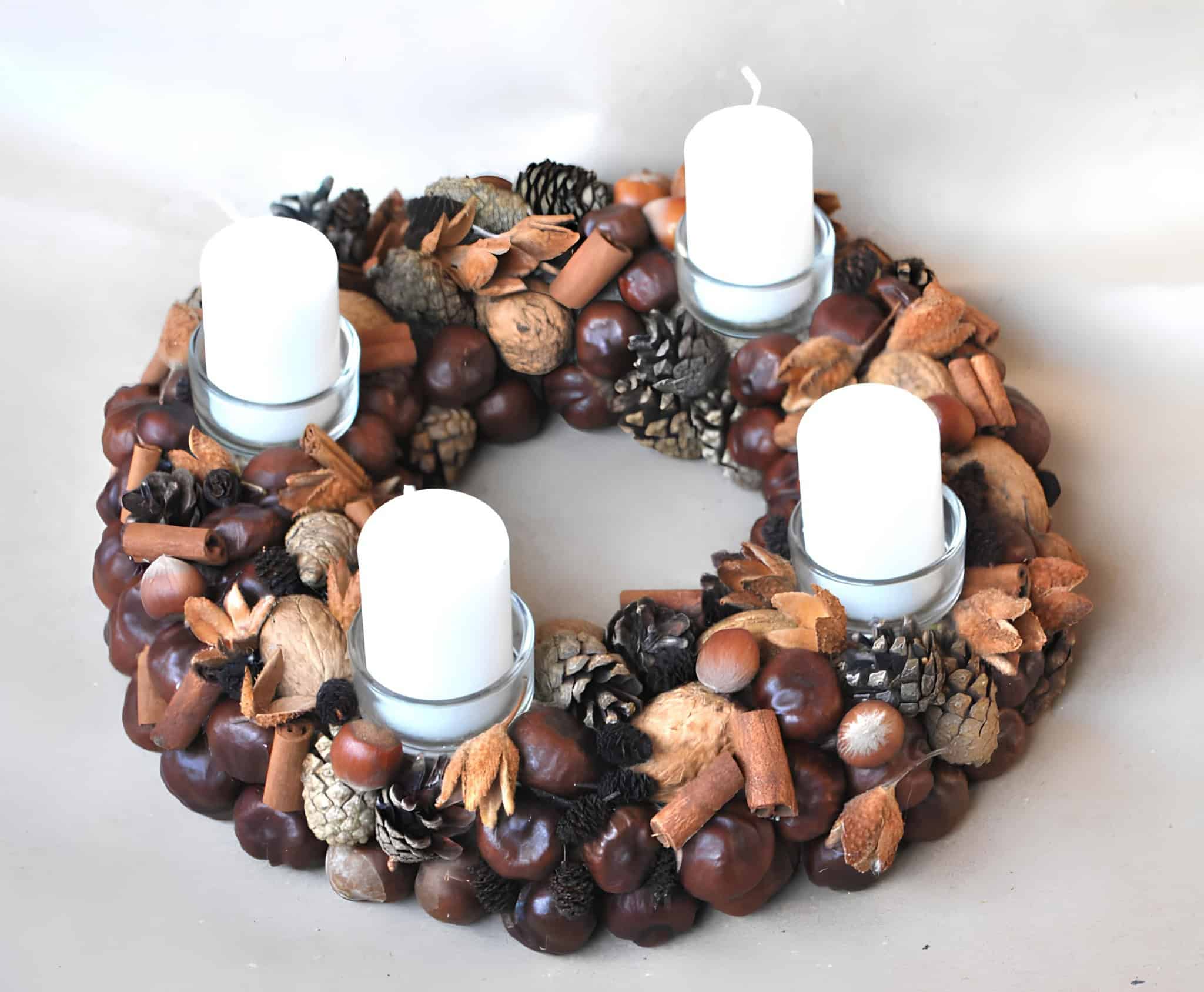 Advent wreath made of pinecones, nuts, cinnamon sticks and white candles