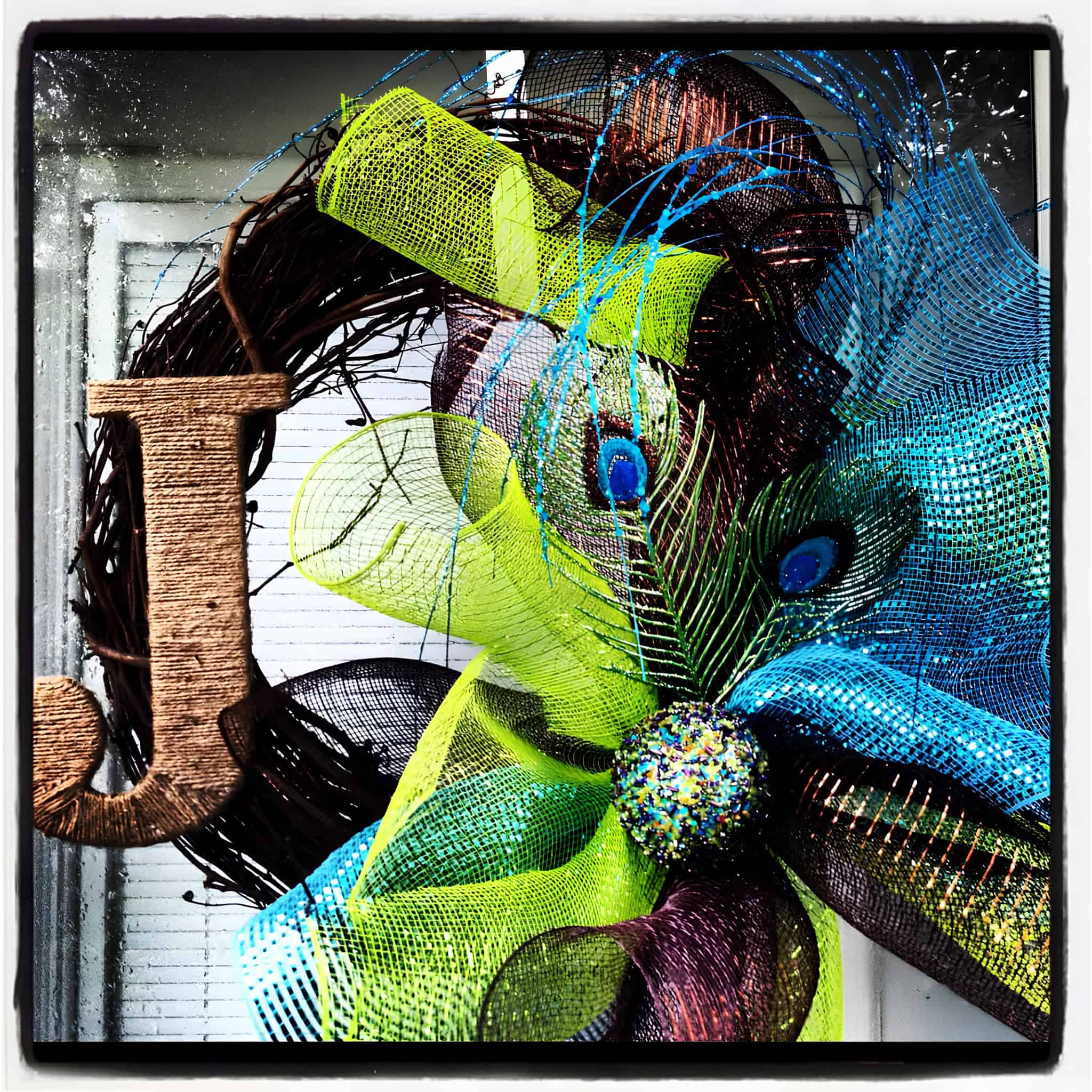 Grapevine base wreath with peacock feathers and mesh ribbon bow in teal and lime