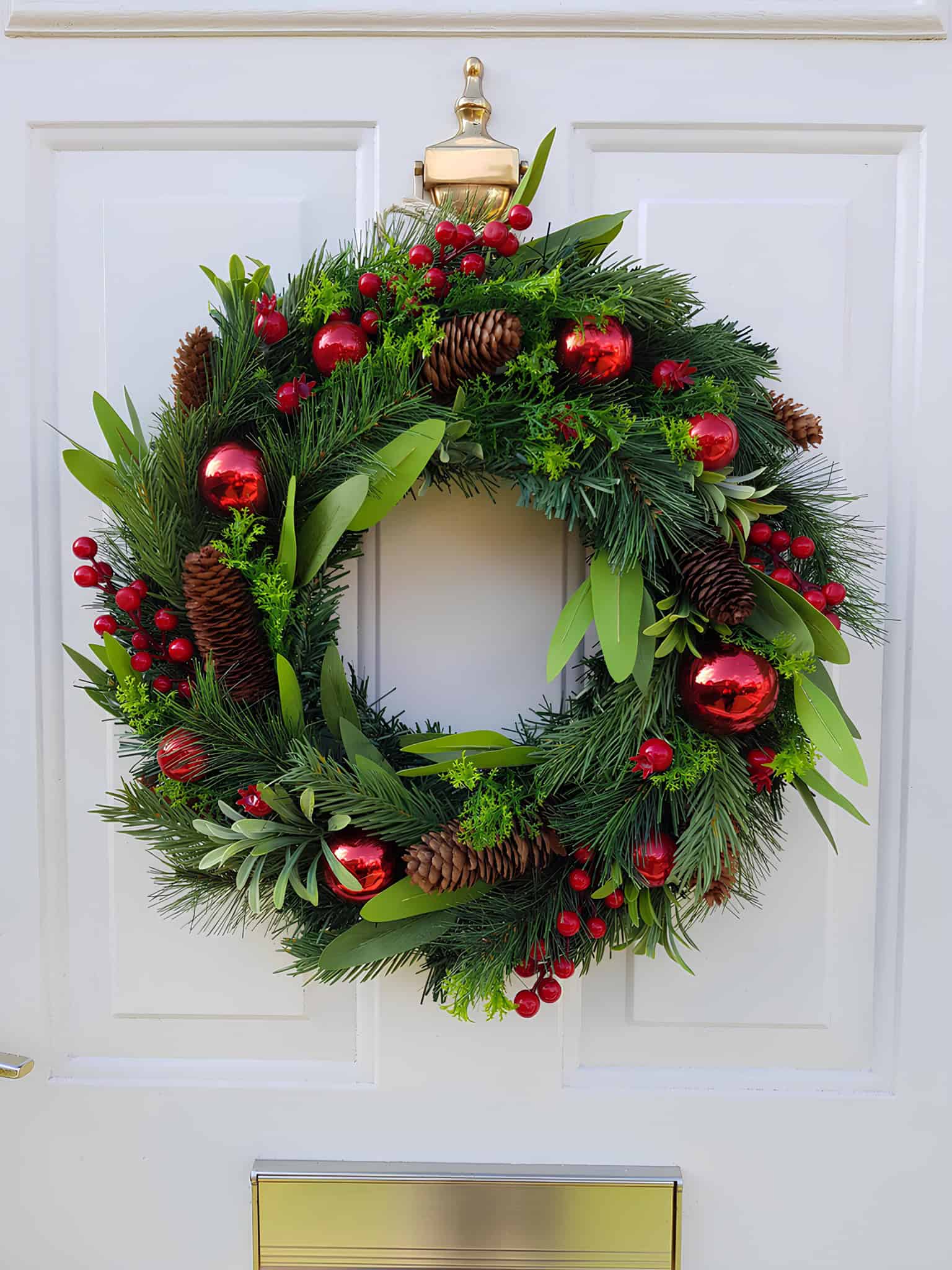 Traditional pine wreath with red ornaments, berries and pinecones