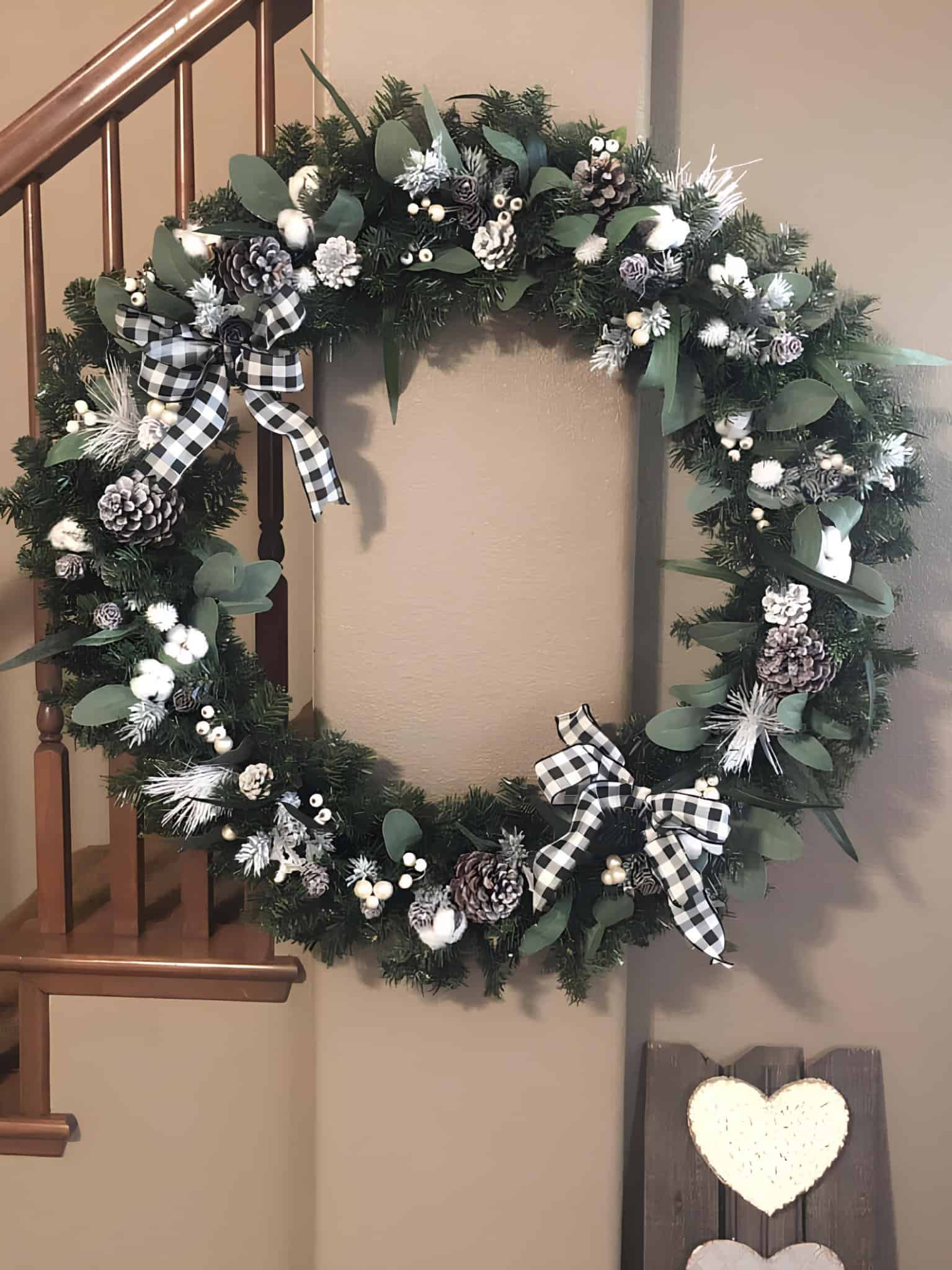 Large holiday wreath with black and white buffalo check bows and frosted pinecones