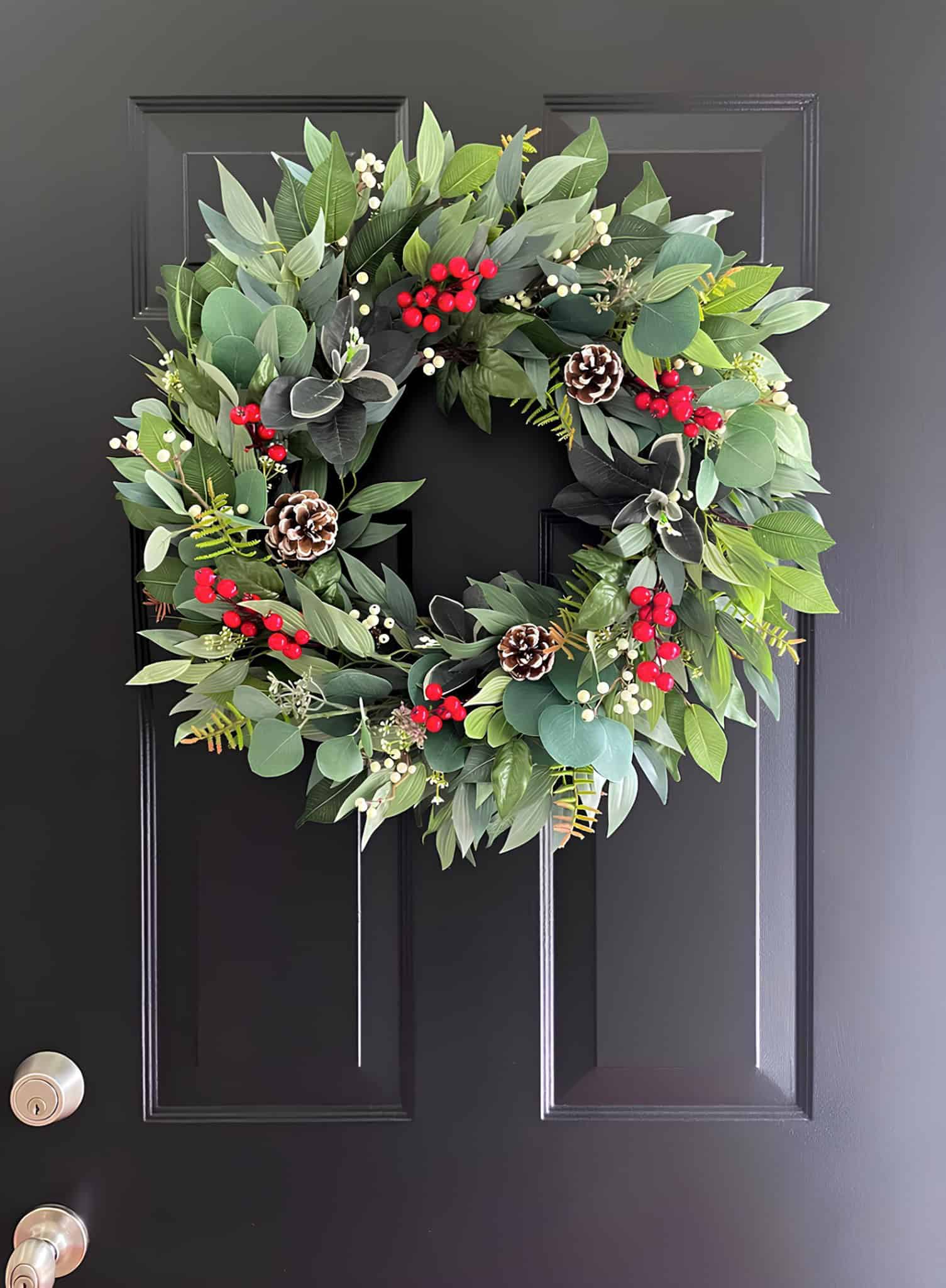 Classic Christmas wreath with mixed greenery, red and white berries, and pinecones