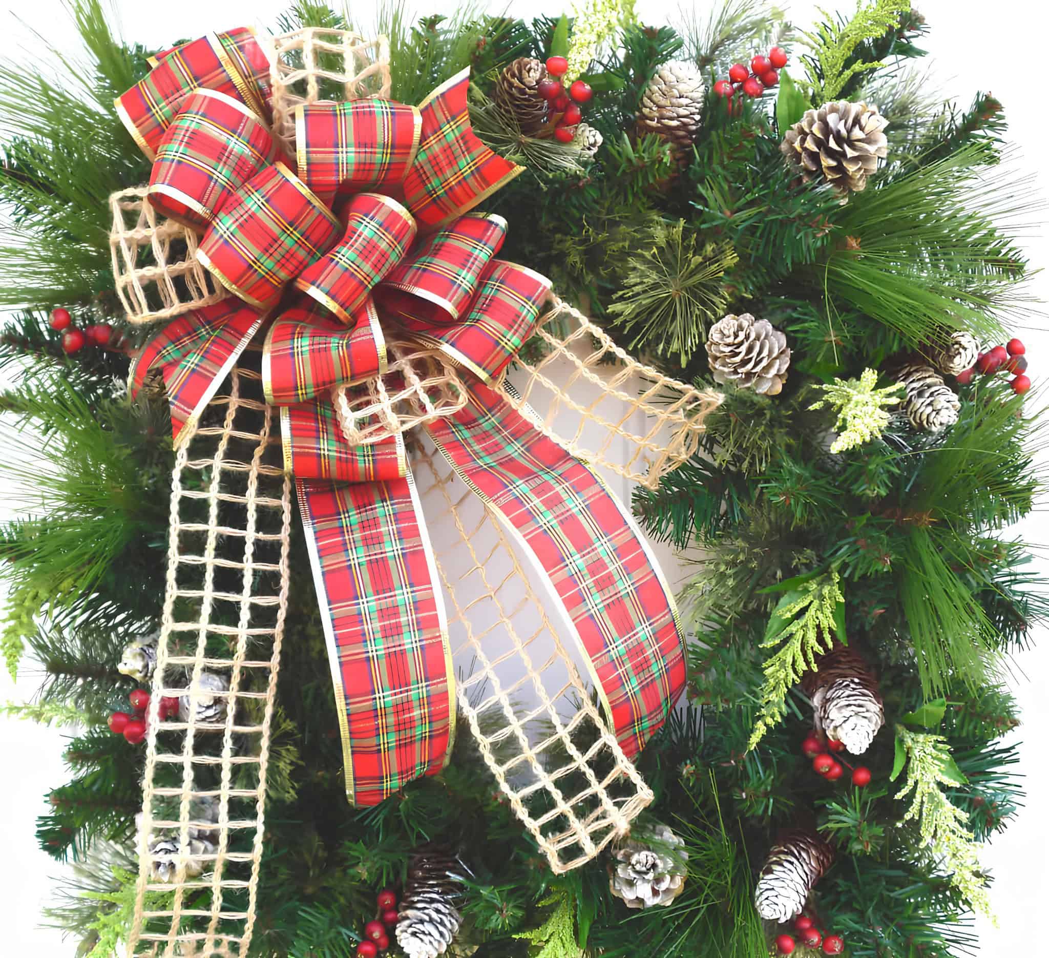 Classic evergreen wreath with tartan plaid bow, pinecones and red berries