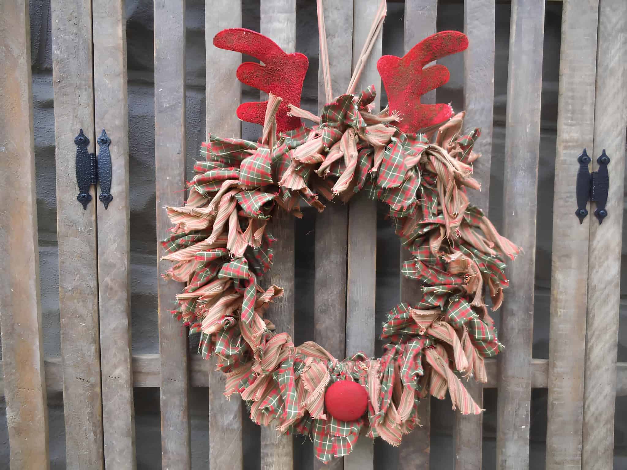 Plaid fabric Christmas wreath with red reindeer antlers and rustic charm
