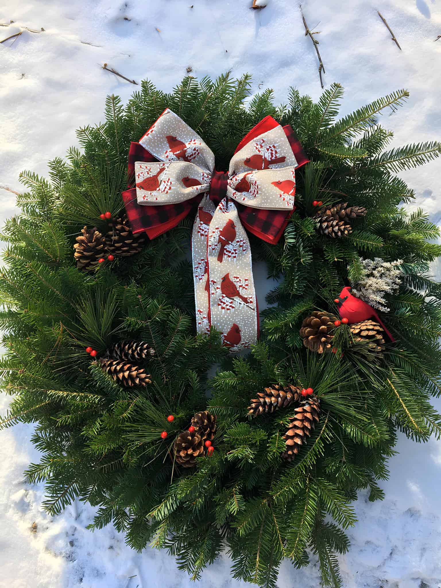 Festive evergreen and pinecone wreath with a red velvet bow, nuts and ornaments