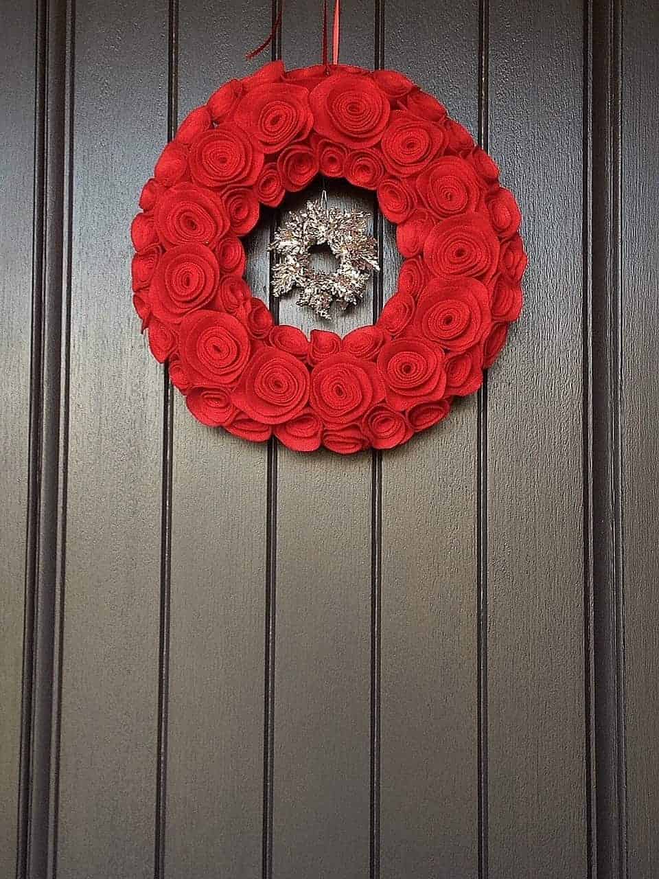 Red felt rose Christmas wreath on dark wood door