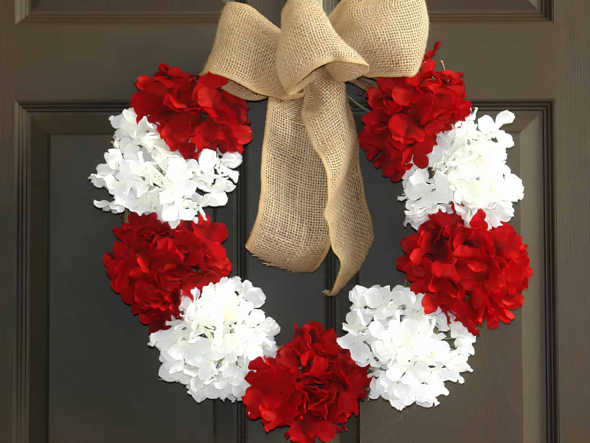Christmas wreath with red and white hydrangeas and a large burlap bow