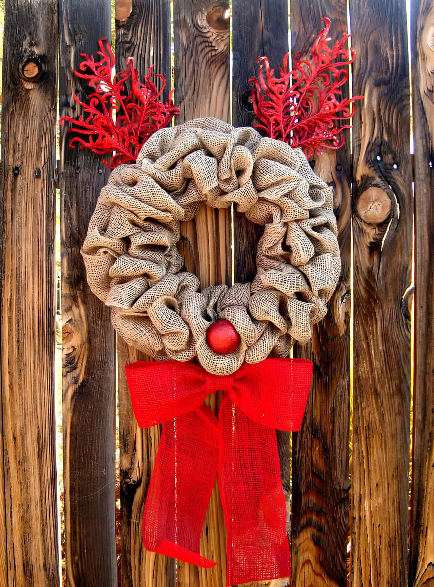 Natural burlap Christmas wreath with red antlers, red nose and a big red bow