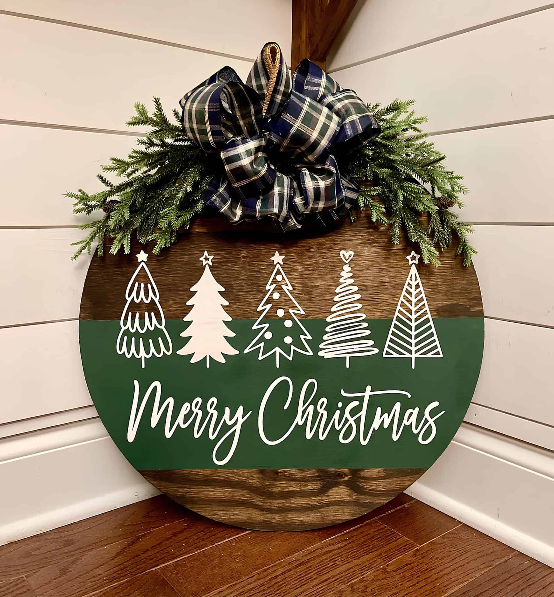 Round wood door sign with greenery, plaid bow and Merry Christmas script