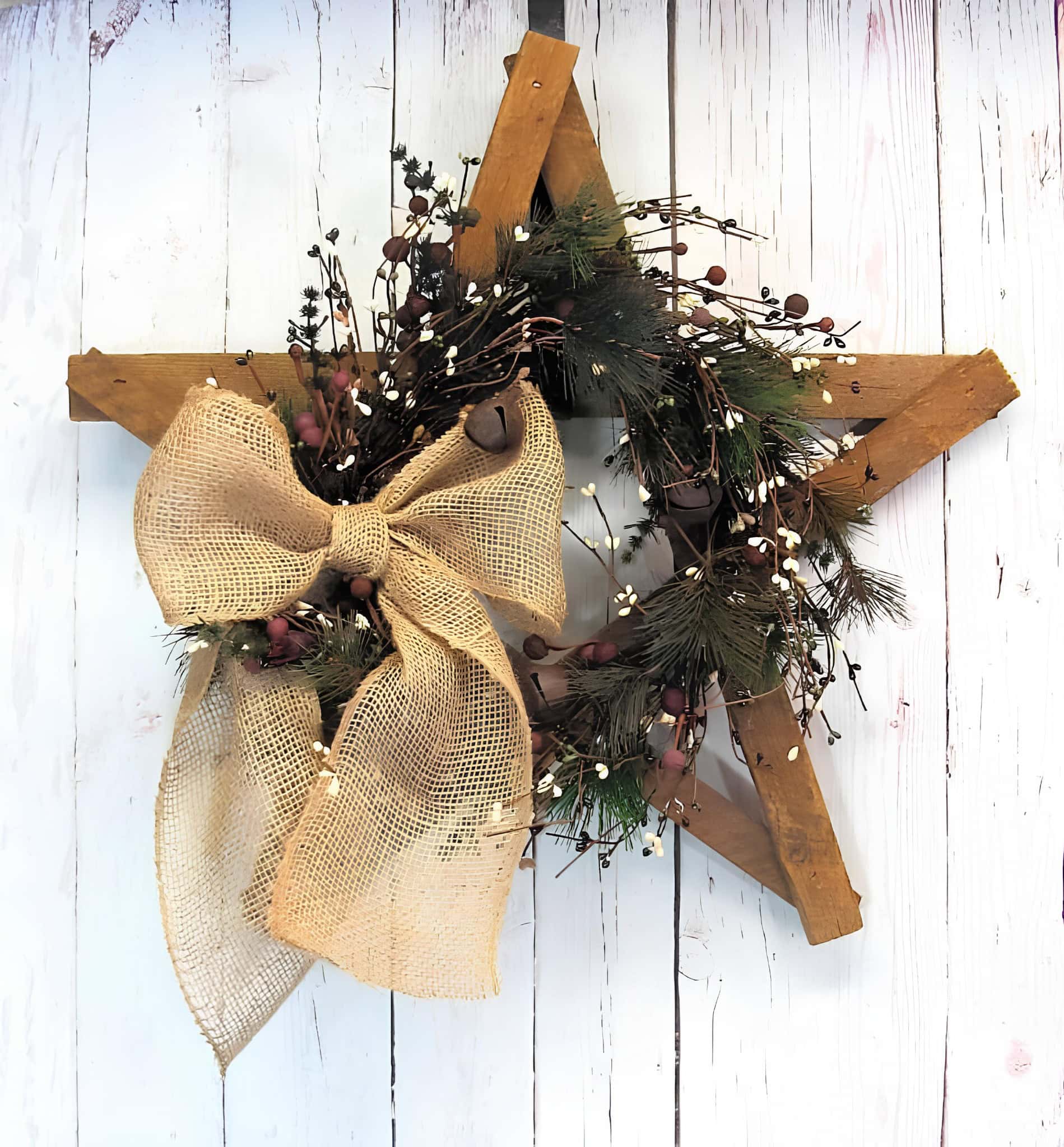 Rustic wooden star wreath with winter greenery and a burlap bow