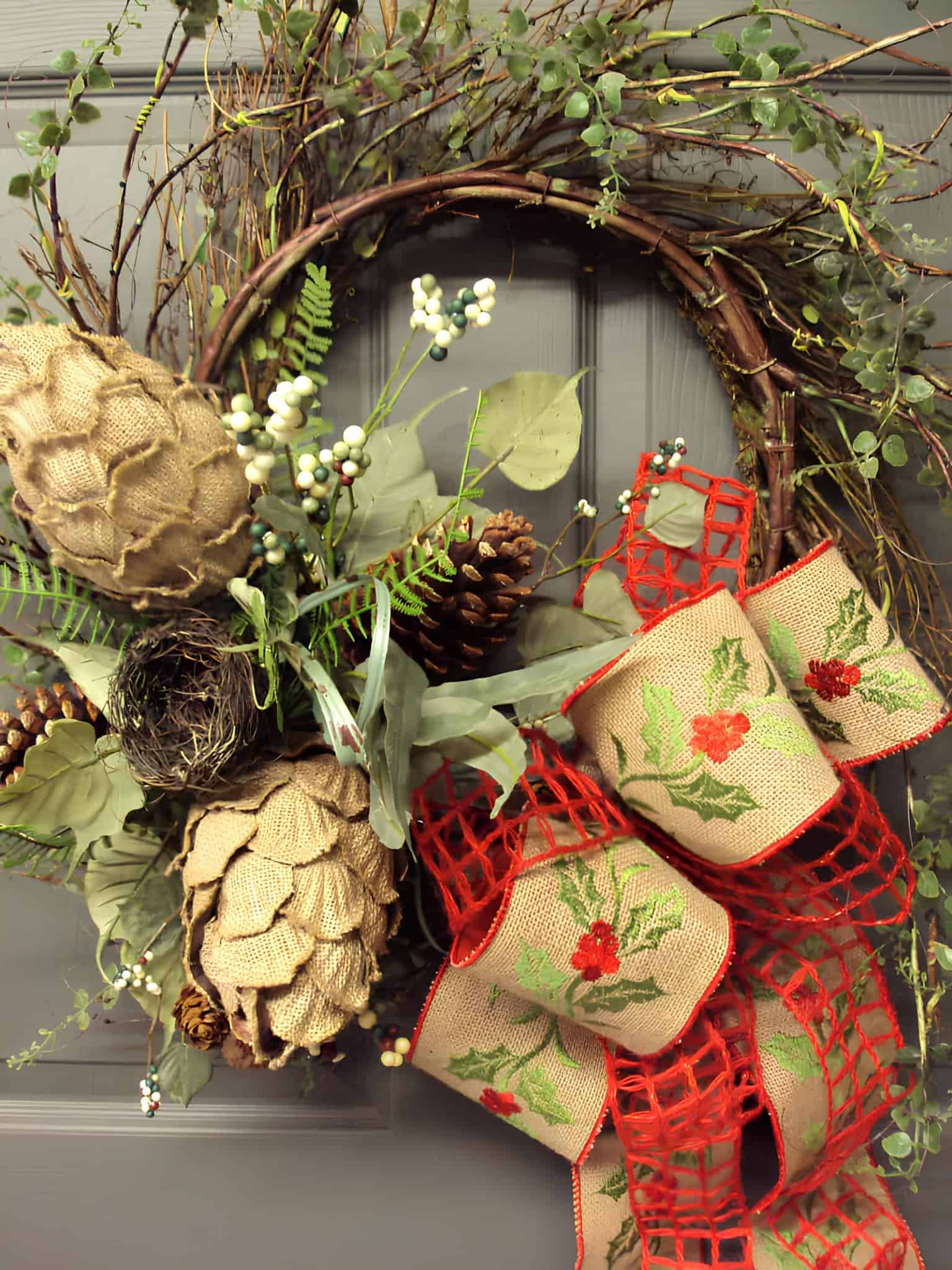 Rustic wooden Christmas wreath on a grapevine base with burlap holly ribbon, pinecones and greenery