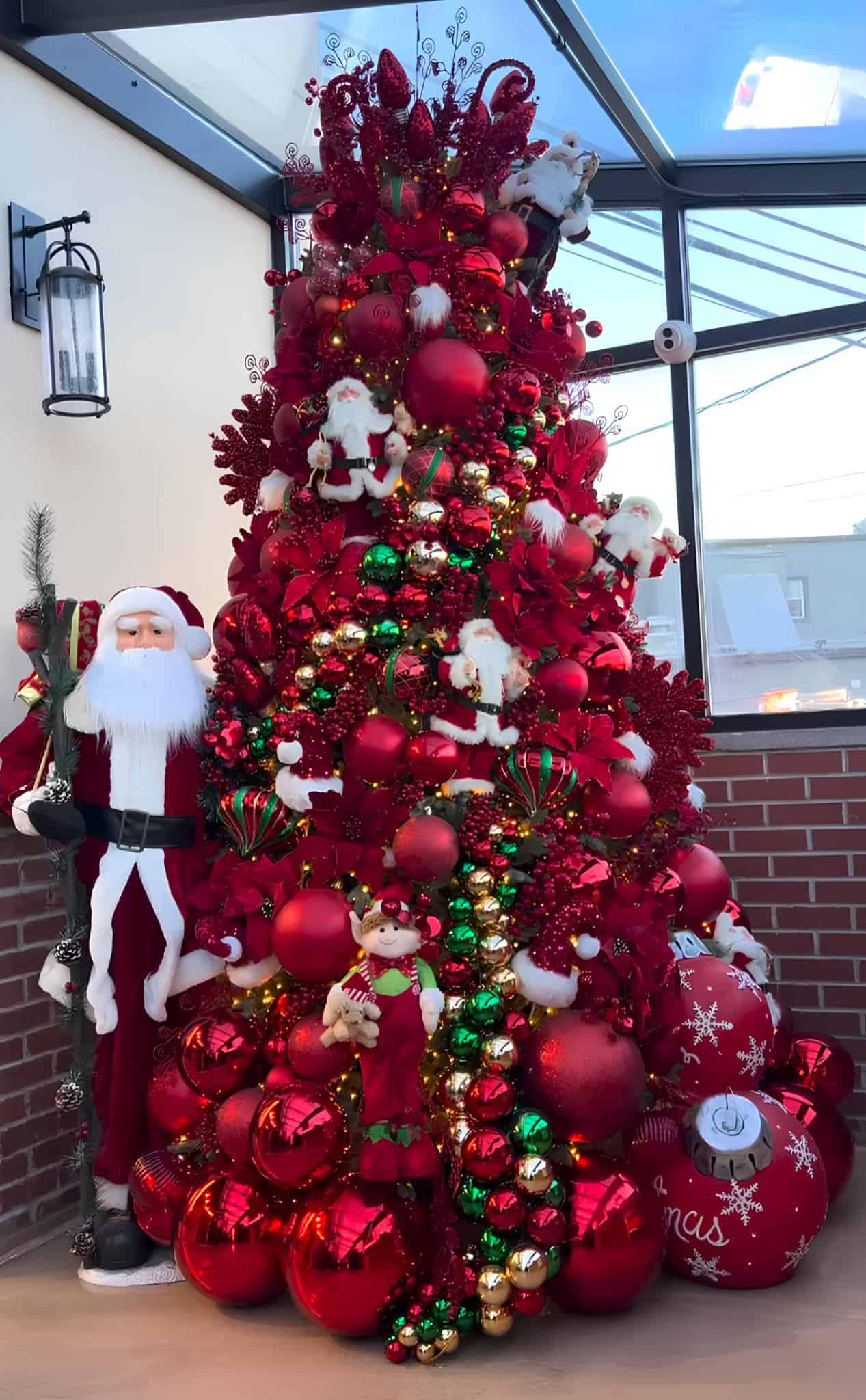 Red Christmas tree with Santa and elf ornaments in traditional style