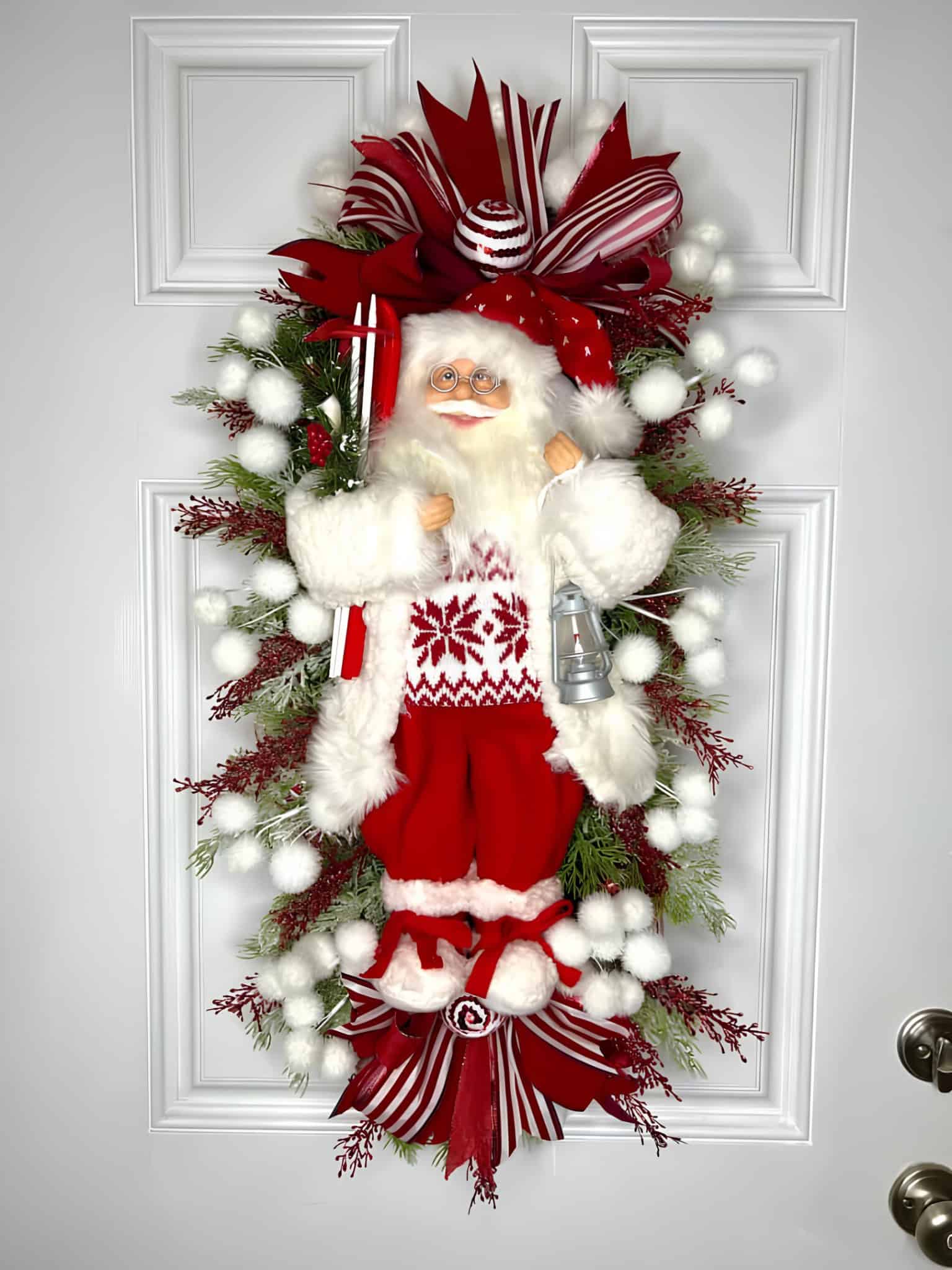 Vertical Santa swag wreath with red and white ribbons and winter greenery