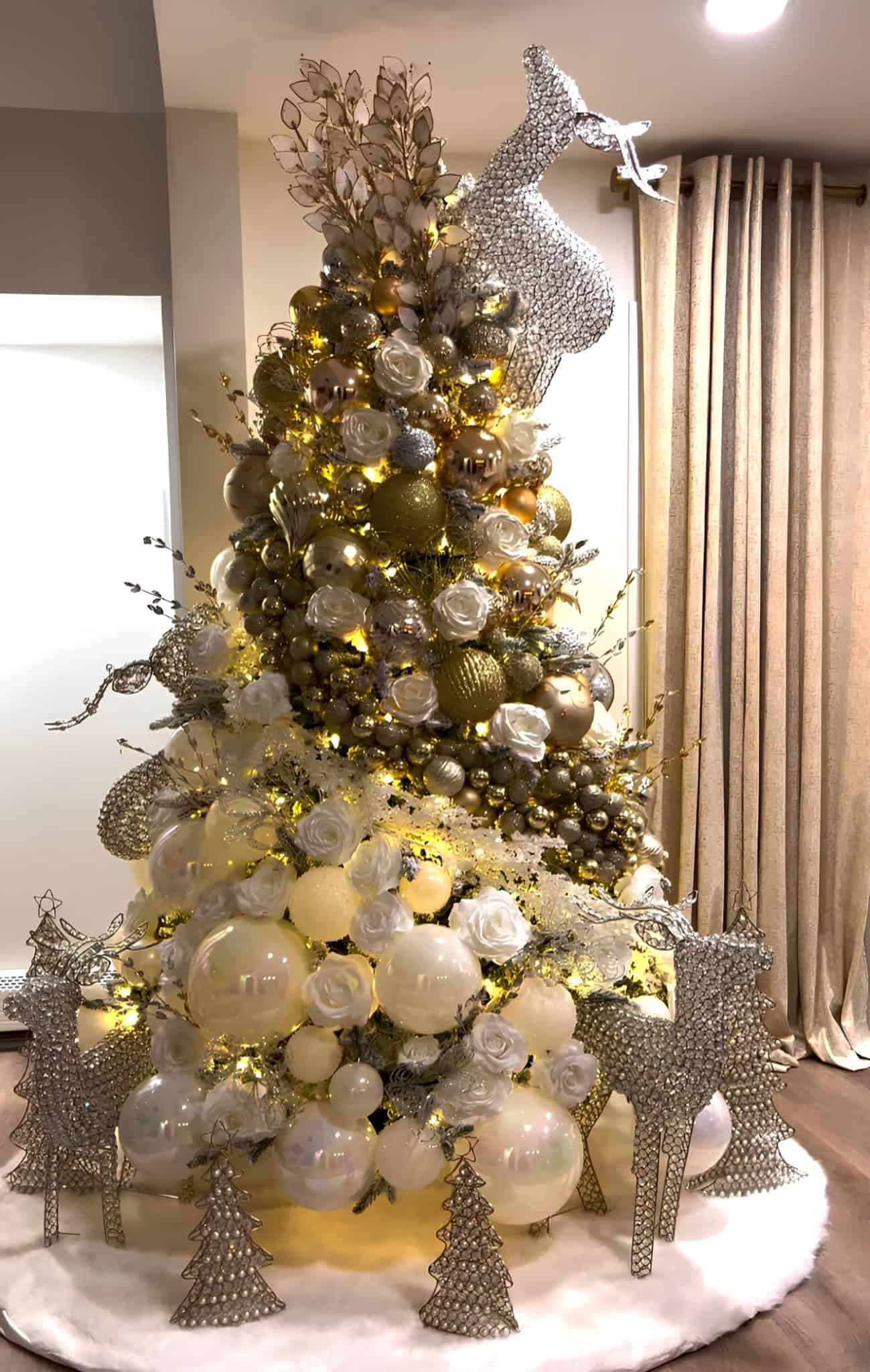 Silver and gold Christmas tree with reindeer figures and glowing ornaments