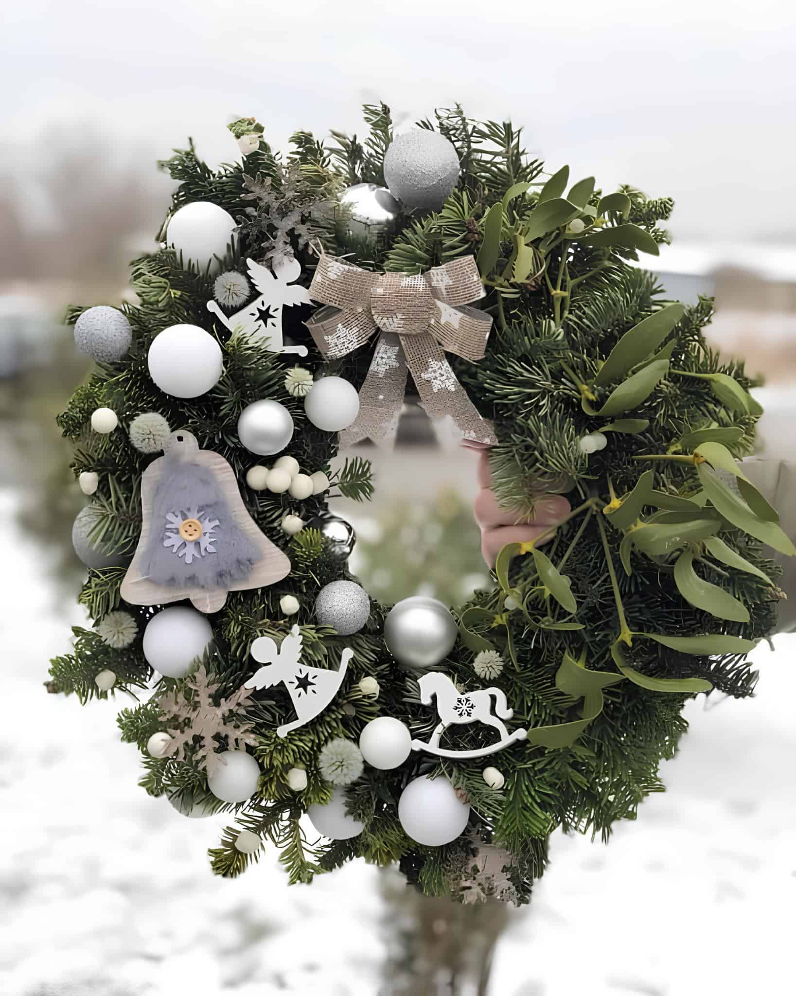 Green wreath with silver and white ornaments, angels, and a neutral bow
