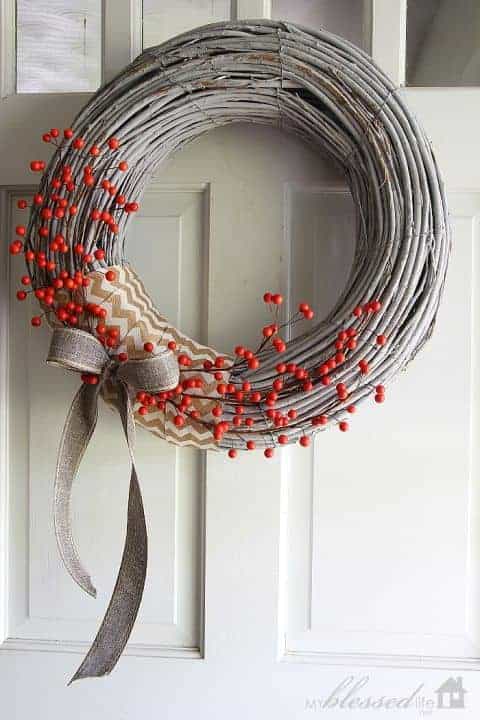 Gray twig wreath decorated with red berries and burlap ribbon