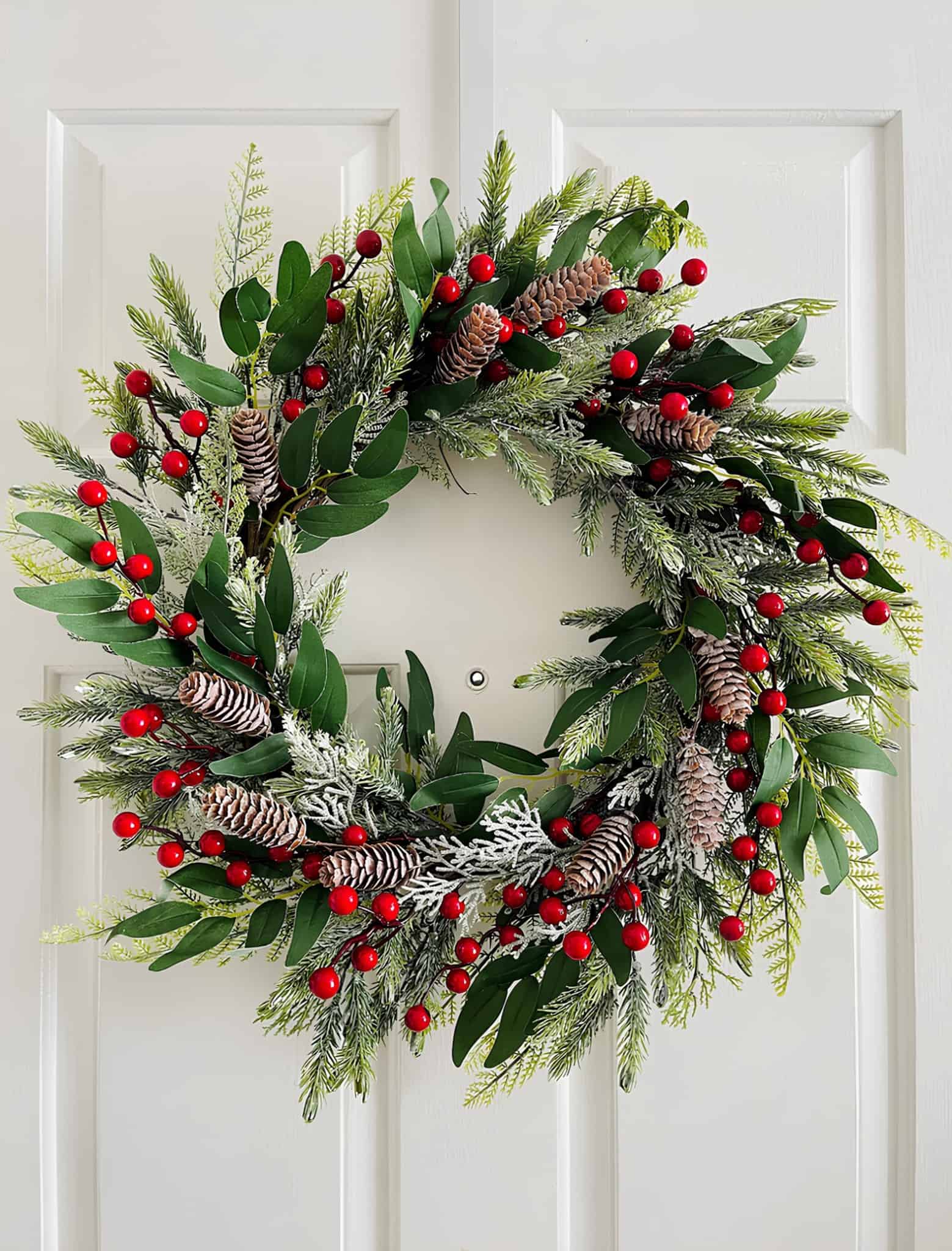 Christmas wreath with eucalyptus, red berries, pinecones, and snowy tips