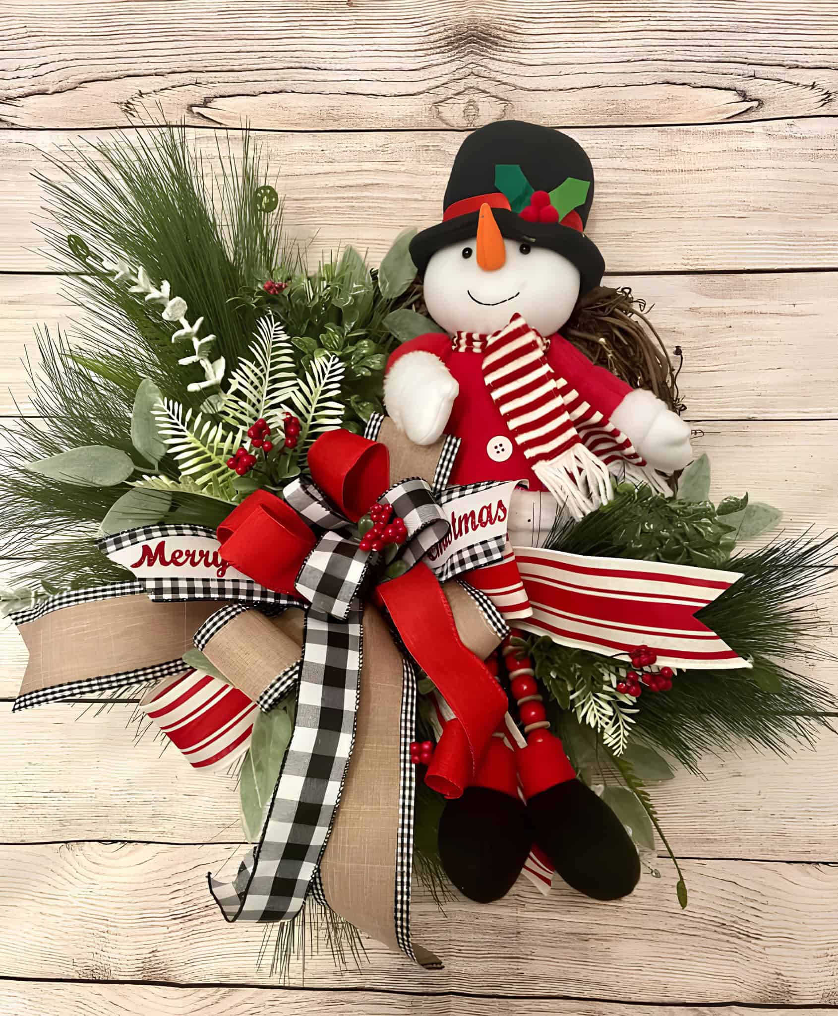 Vibrant Christmas snowman decoration with festive ribbons, greenery, and holiday accents on a wooden background.