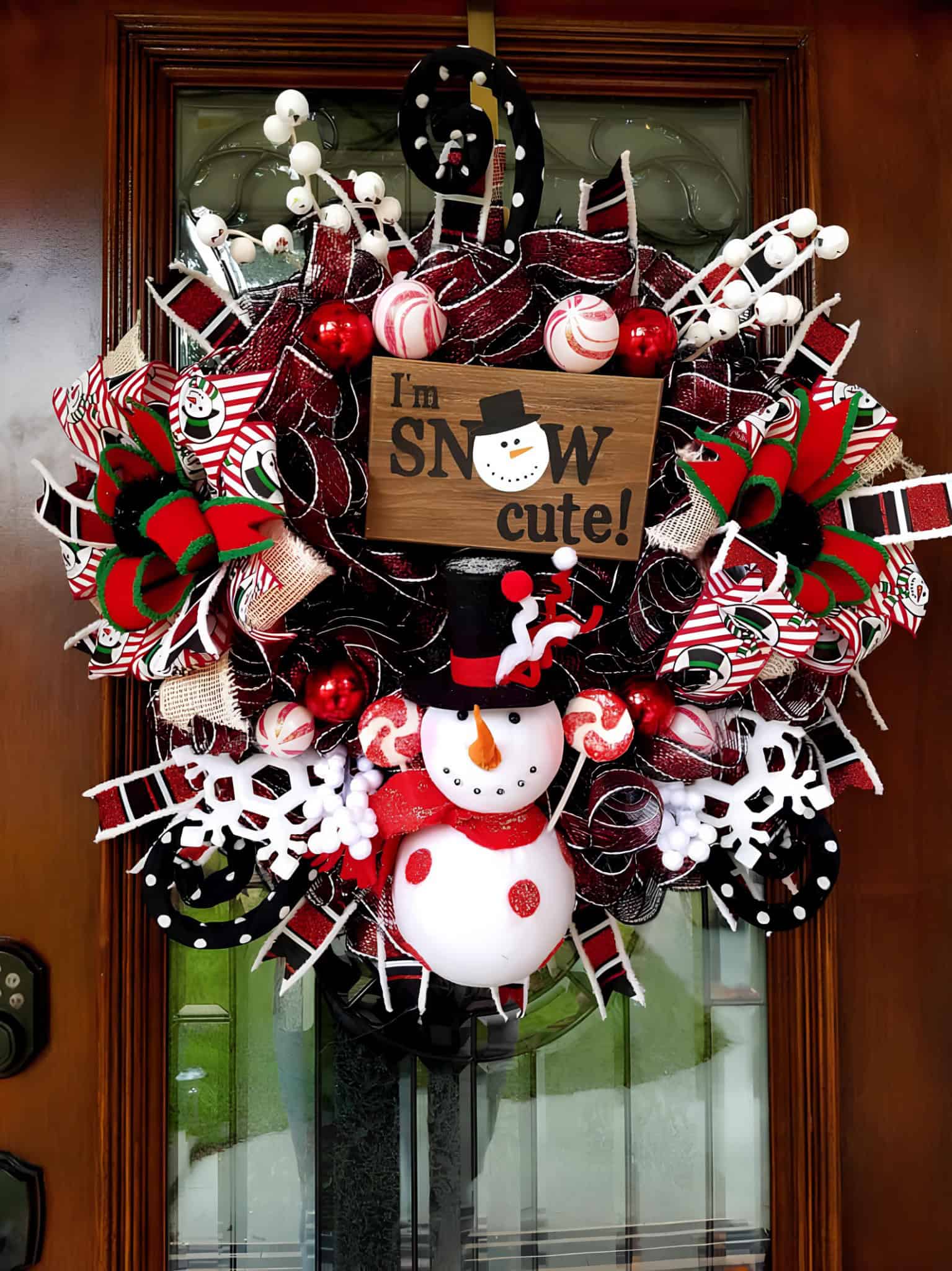 Whimsical ribbon wreath with plush snowman, peppermint ornaments and snowflakes