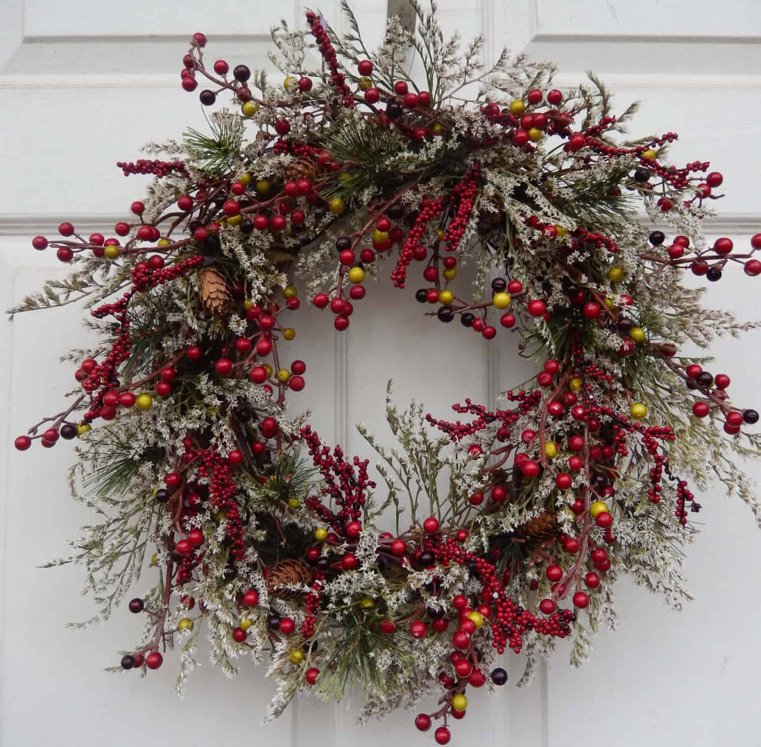 Snow-covered mixed berry Christmas wreath with yellow accents
