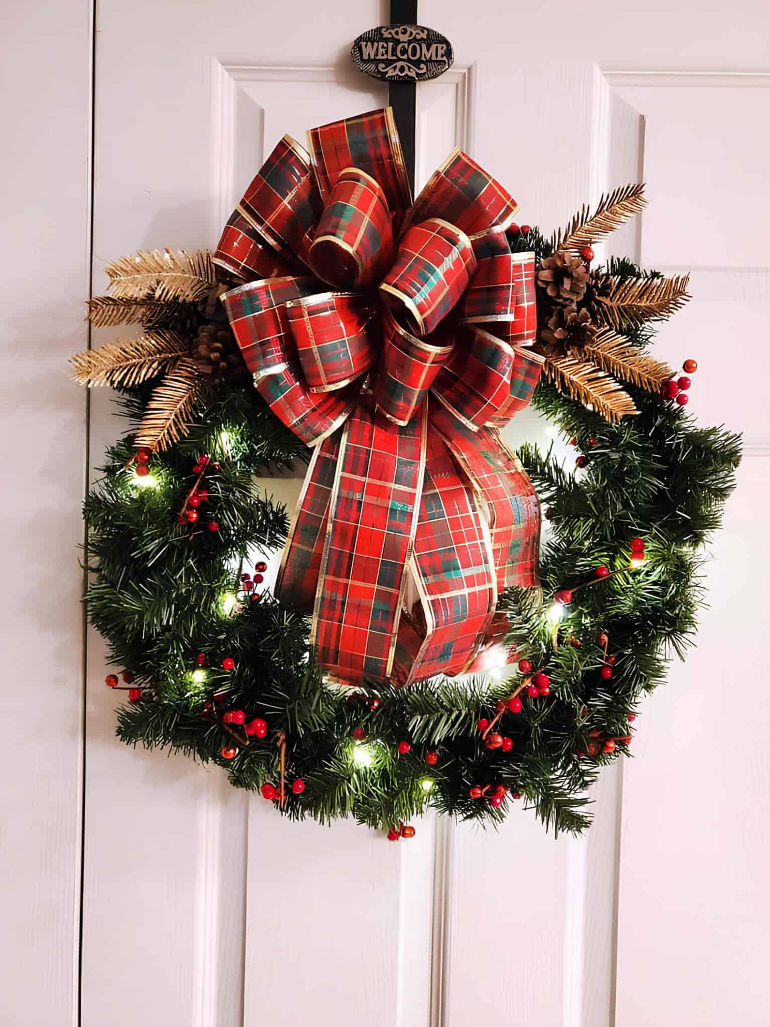 Lighted evergreen Christmas wreath with red tartan bow and berries