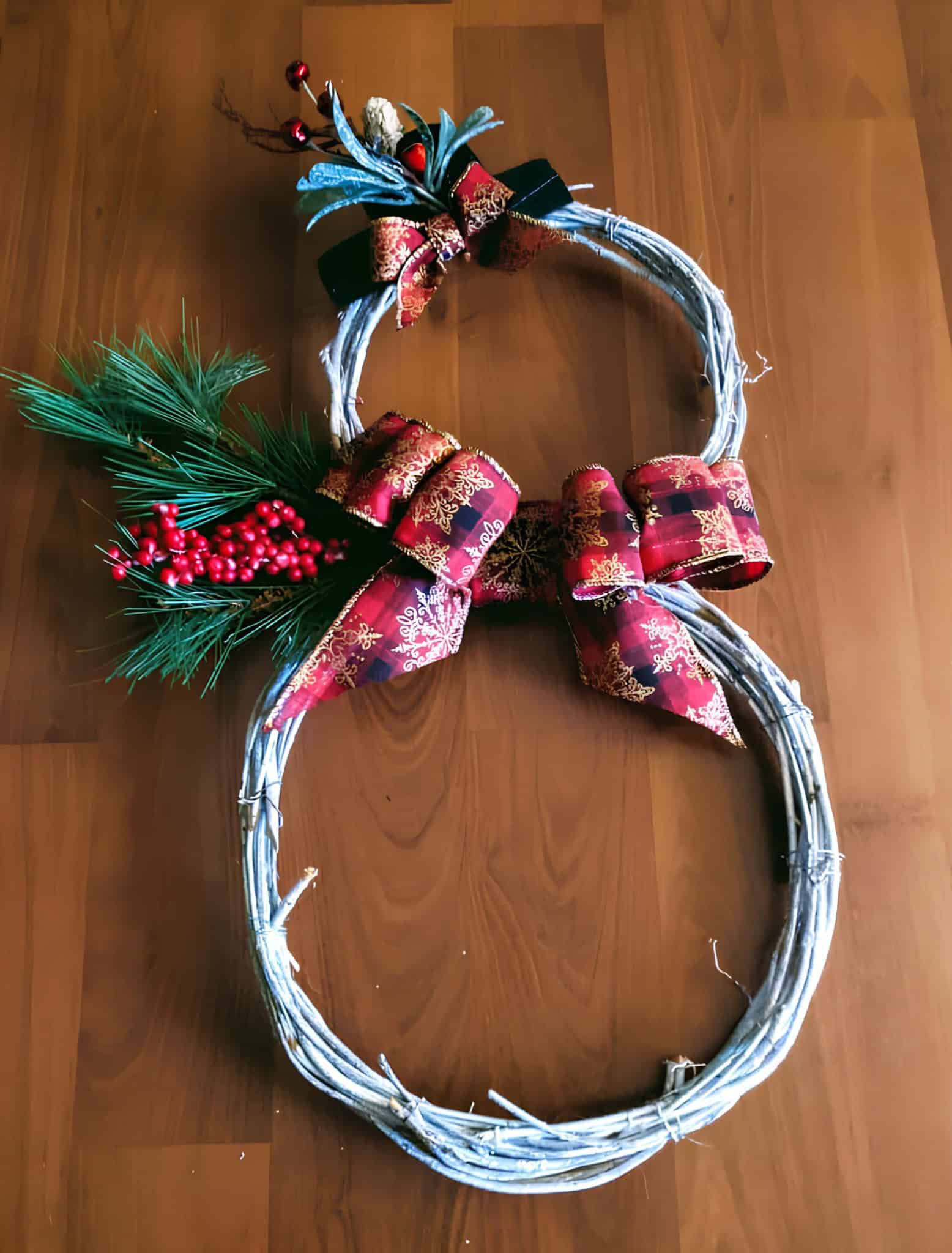 Festive Christmas wreath with red ribbons, pine branches, and berries for holiday home décor.