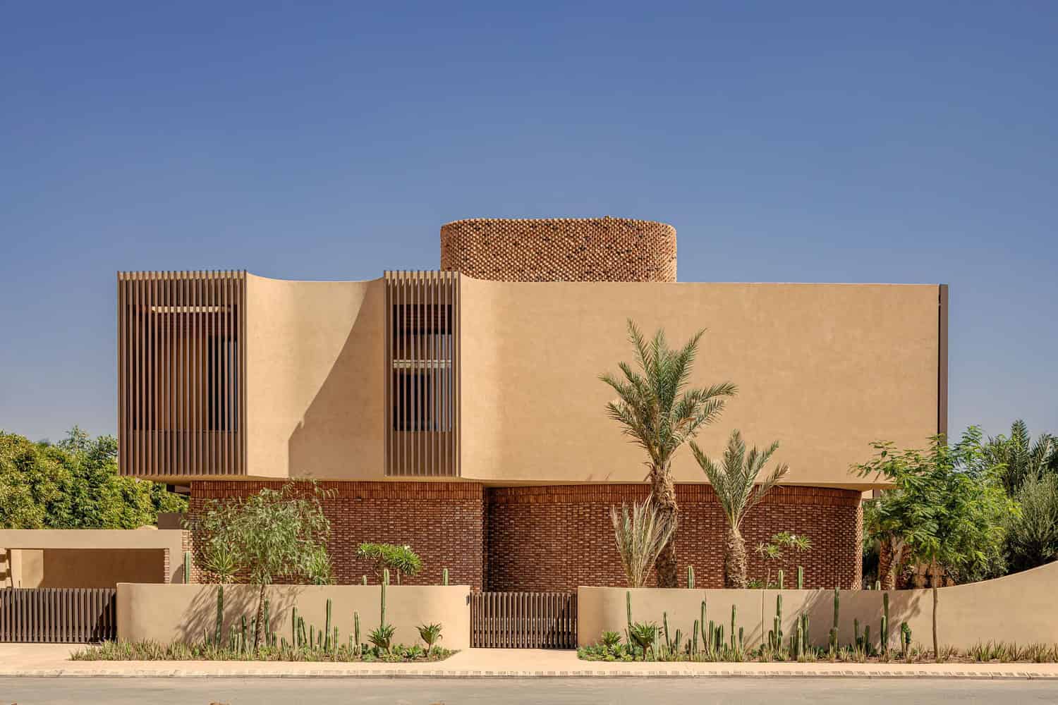 Modern desert house with contemporary architecture, incorporating natural materials and minimalistic design elements, surrounded by desert landscaping and palm trees.