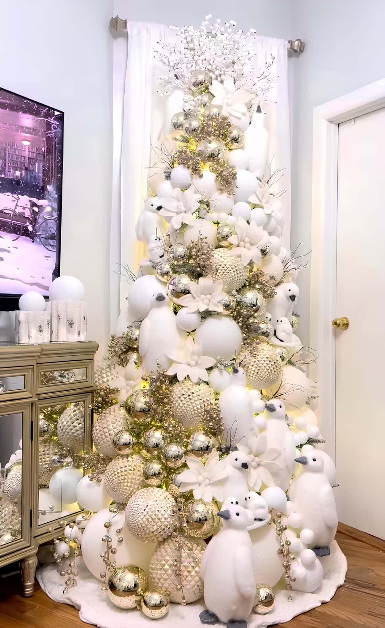 White and gold Christmas tree with penguin figurines and textured ornaments