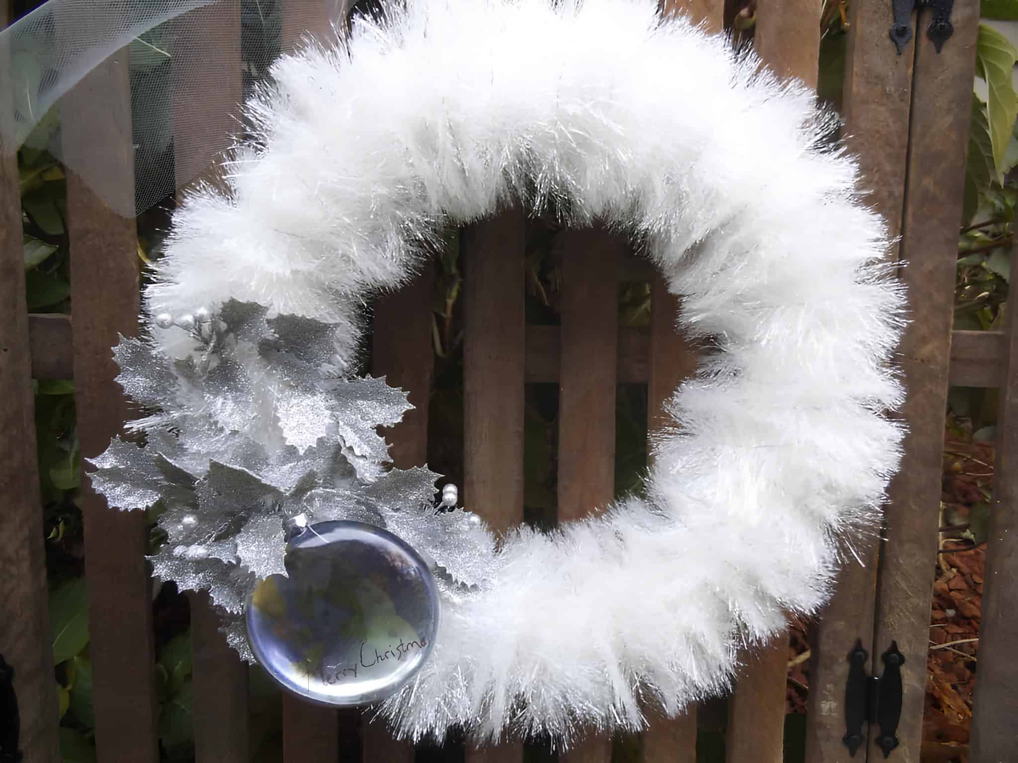 White tinsel Christmas wreath with silver leaves and a hanging ornament