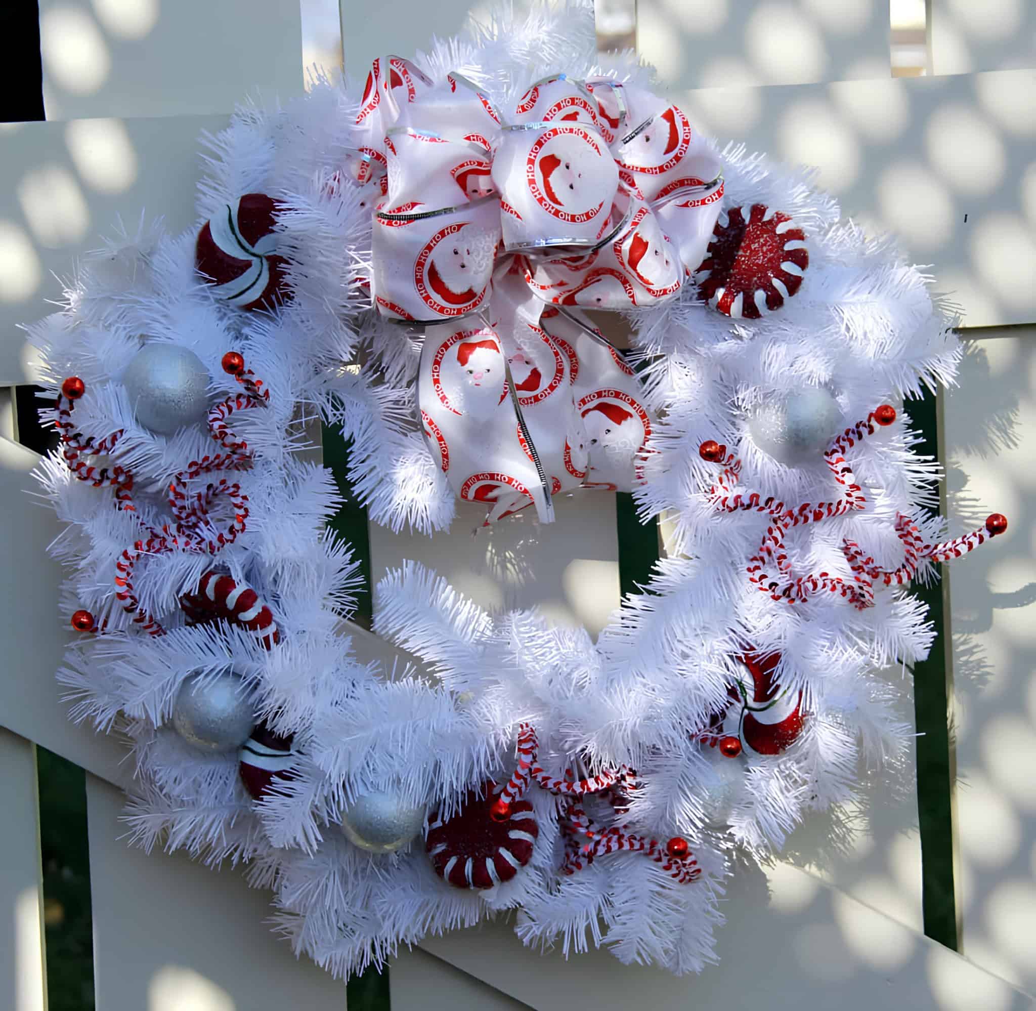 White tinsel wreath with peppermint ornaments, curly picks and Santa ribbon bow