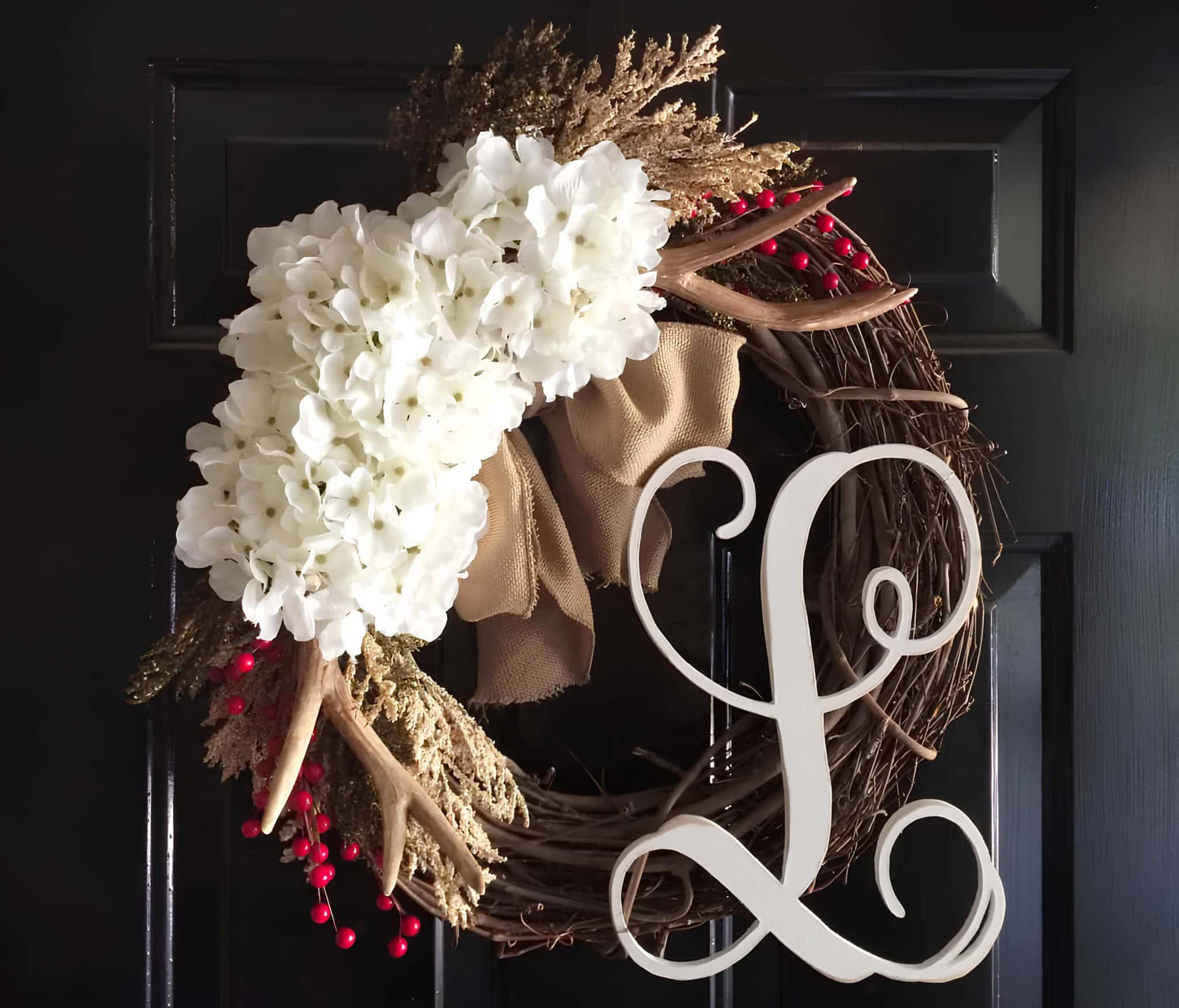 Rustic wooden wreath with white hydrangeas, antlers, burlap bow and a script monogram